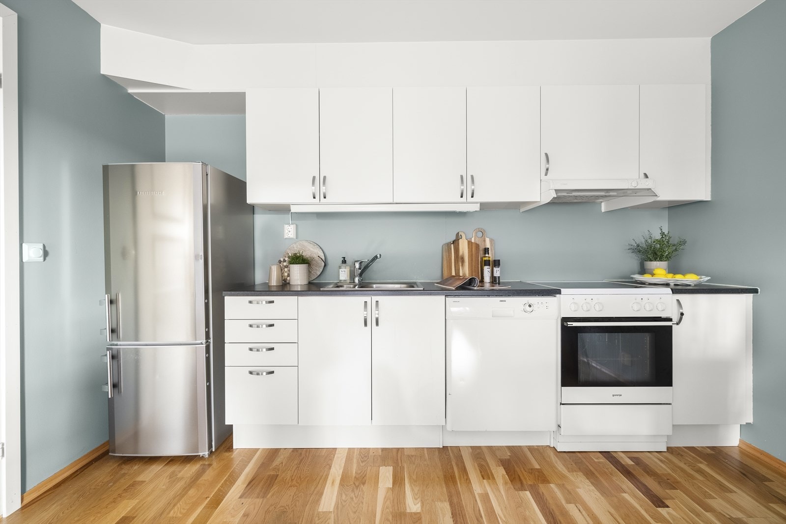 Kjøkkenet har glatte fronter og laminat benkeplate med nedfelt vaskekum, praktiske overskap til oppbevaring, frittstående komfyr med ventilator er plassert over kokeplass samt oppvaskmaskin og frittstående kjøleskap. Galleribilde