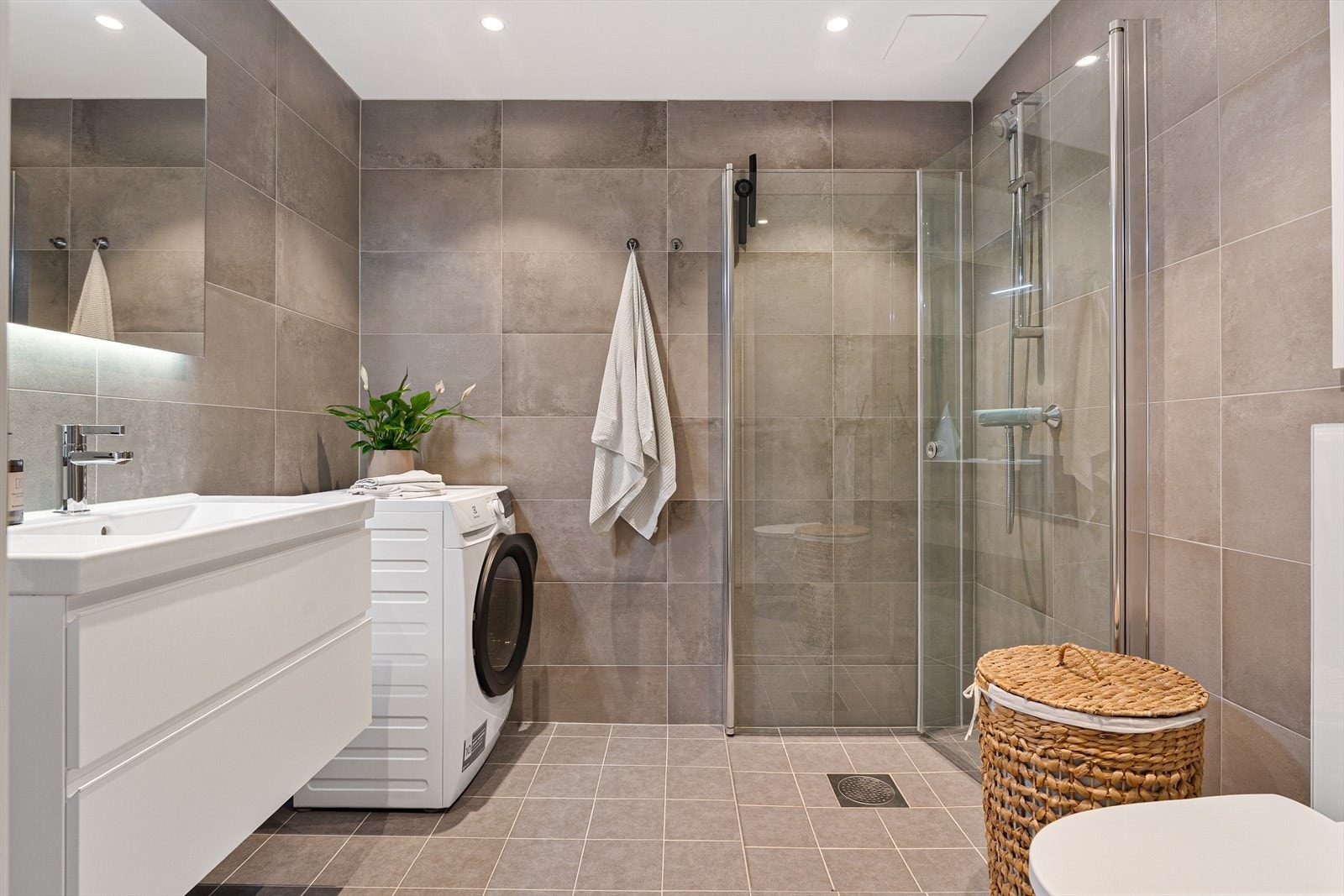 Nydelig bad på 4,6m² med varmekabler i gulv, romslig dusjhjørne og opplegg til vaskemaskin. Galleribilde