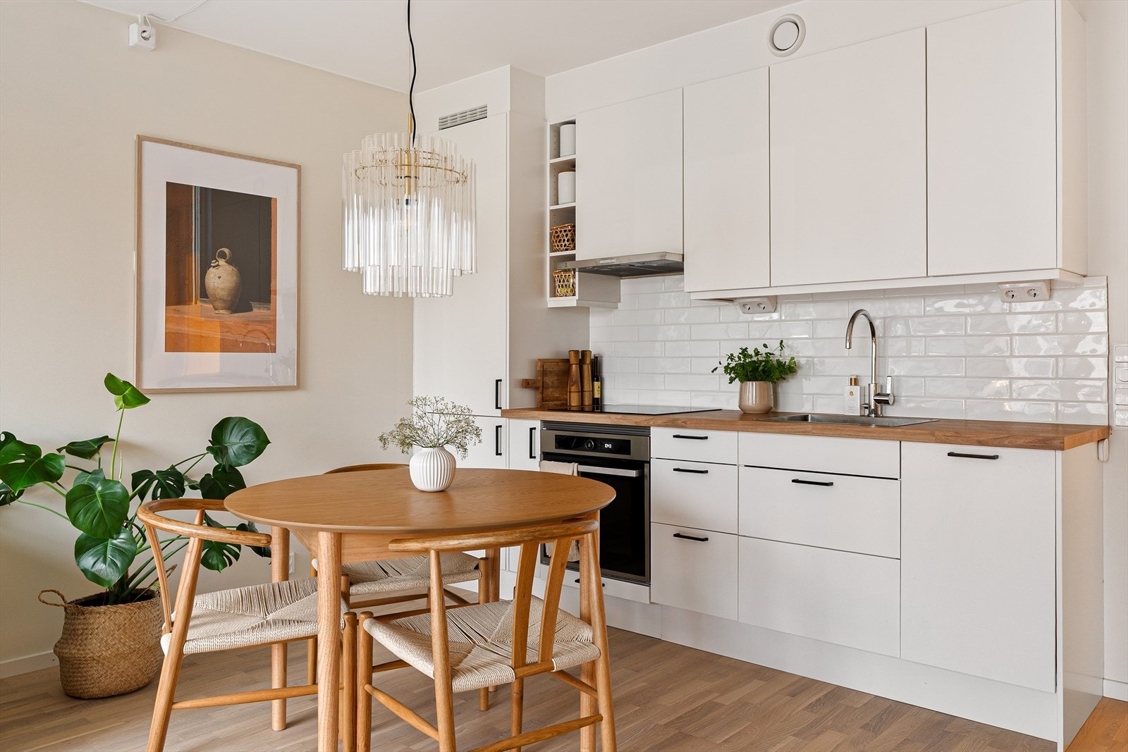 Lys, tidløs kjøkkeninnredning med integrerte hvitevarer medfølger i handelen. Selger har oppgradert vegg under høyskap med stilrene fliser. Galleribilde