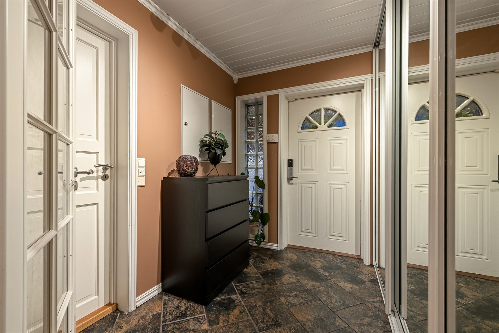 Entreen har flislagt gulv og praktisk speildørsgarderobe. Elektronisk kodelås på inngangsdøren gjør nøkler overflødige. Vaskerommet til venstre. Galleribilde