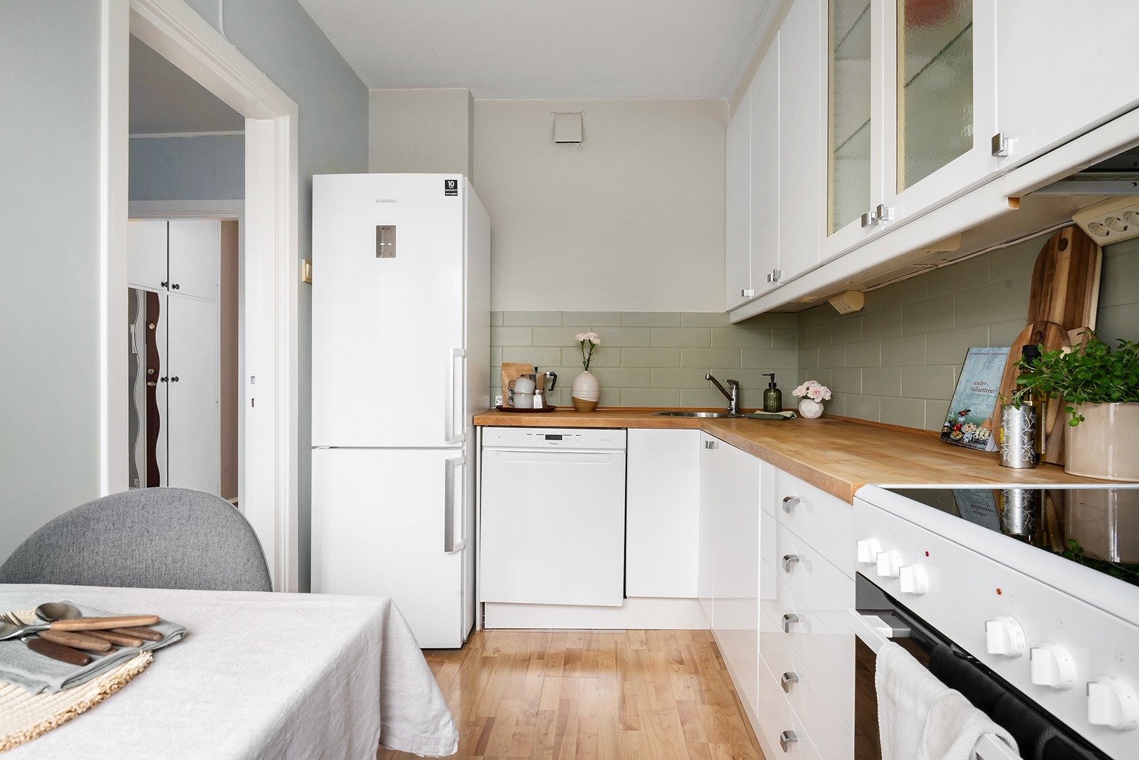 Tidløs kjøkkeninnredning med glatte fronter og heltre benkeplate. Det er belysning under overskapene, samt ventilator med kullfilter og opplegg for oppvaskmaskin. Galleribilde