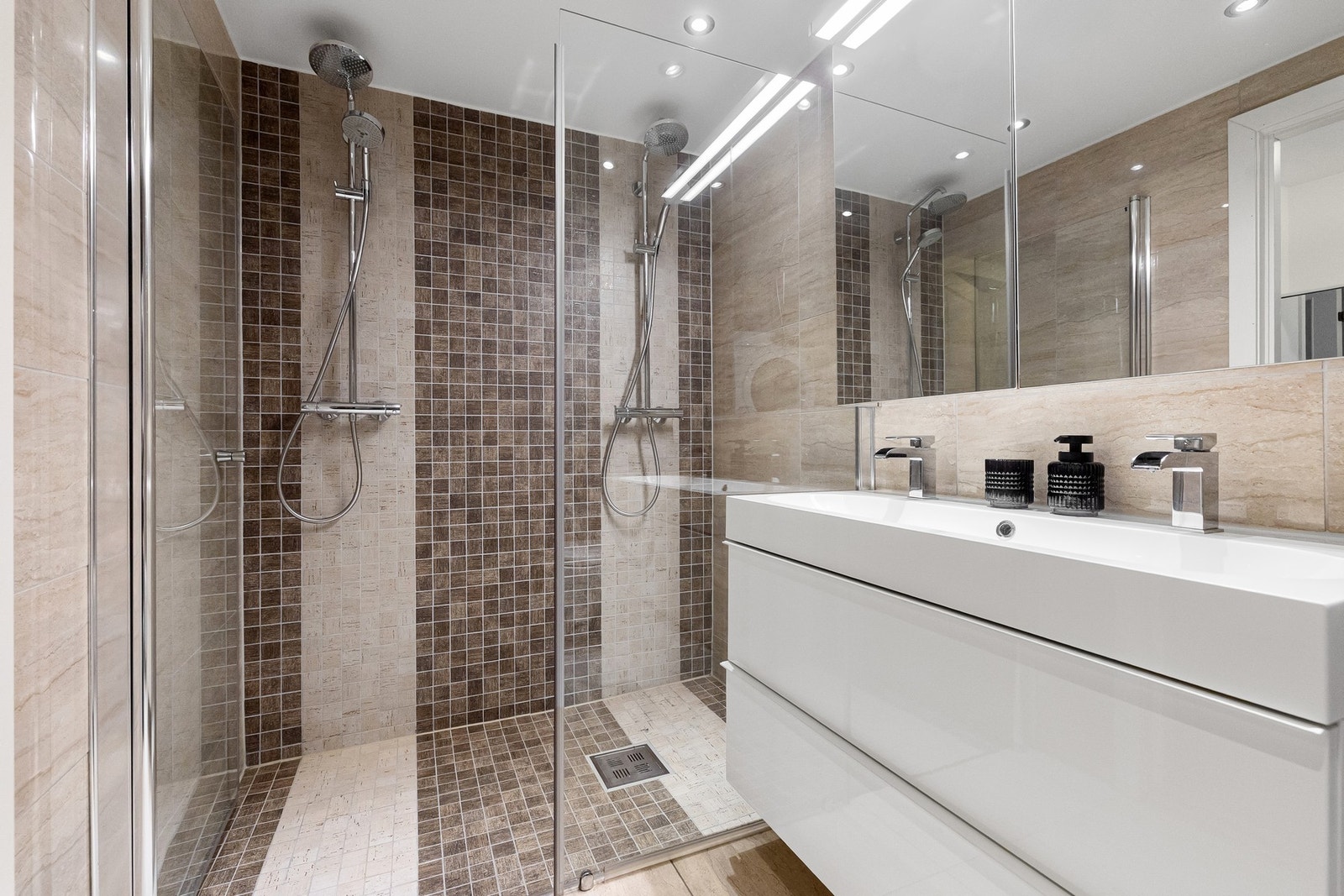 Badet er innredet med vegghengt servantinnredning, speilskap med belysning, dusjhjørne med glassdør, samt vegghengt toalett Galleribilde