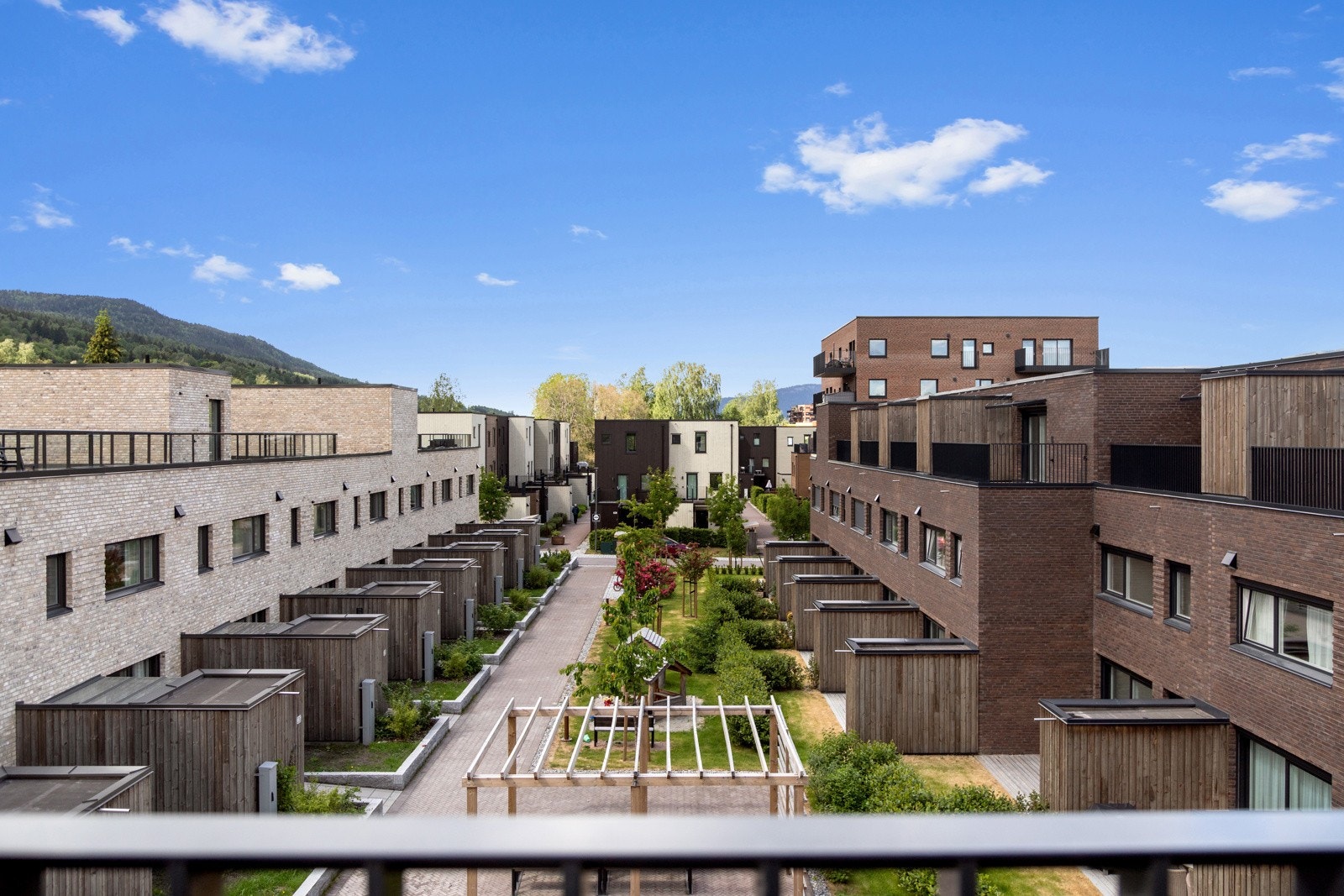 Utsikt mot stor grønt atrium fra takterrassen i toppetasjon | flotte teglfasader tilfører huset liv og tekstur, og understreker følelsen av kvalitet Galleribilde