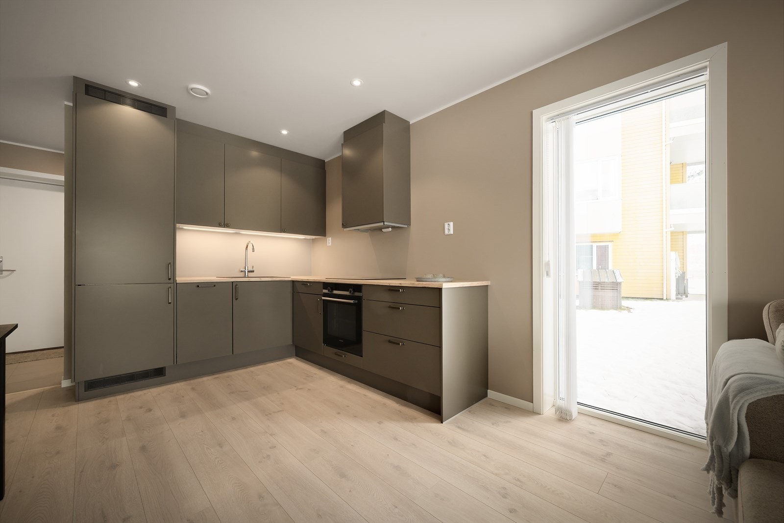 Lekkert Sigdal kjøkken med takhøge overskåp. LED spottar lyser godt opp benkeplate i heiltre eik Galleribilde