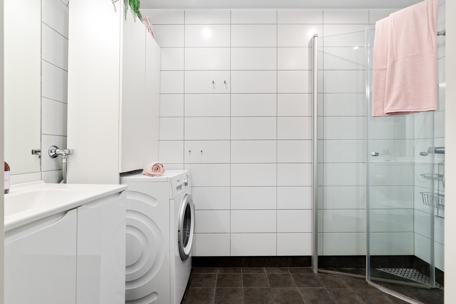 Flislagt bad med stilrene fargevalg. Videre er det baderomsinnredning med servant, toalett, dusj med dusjvegger og vegghengt armatur, opplegg for vaskemaskin/tørketrommel og behagelig varme i gulv. Galleribilde