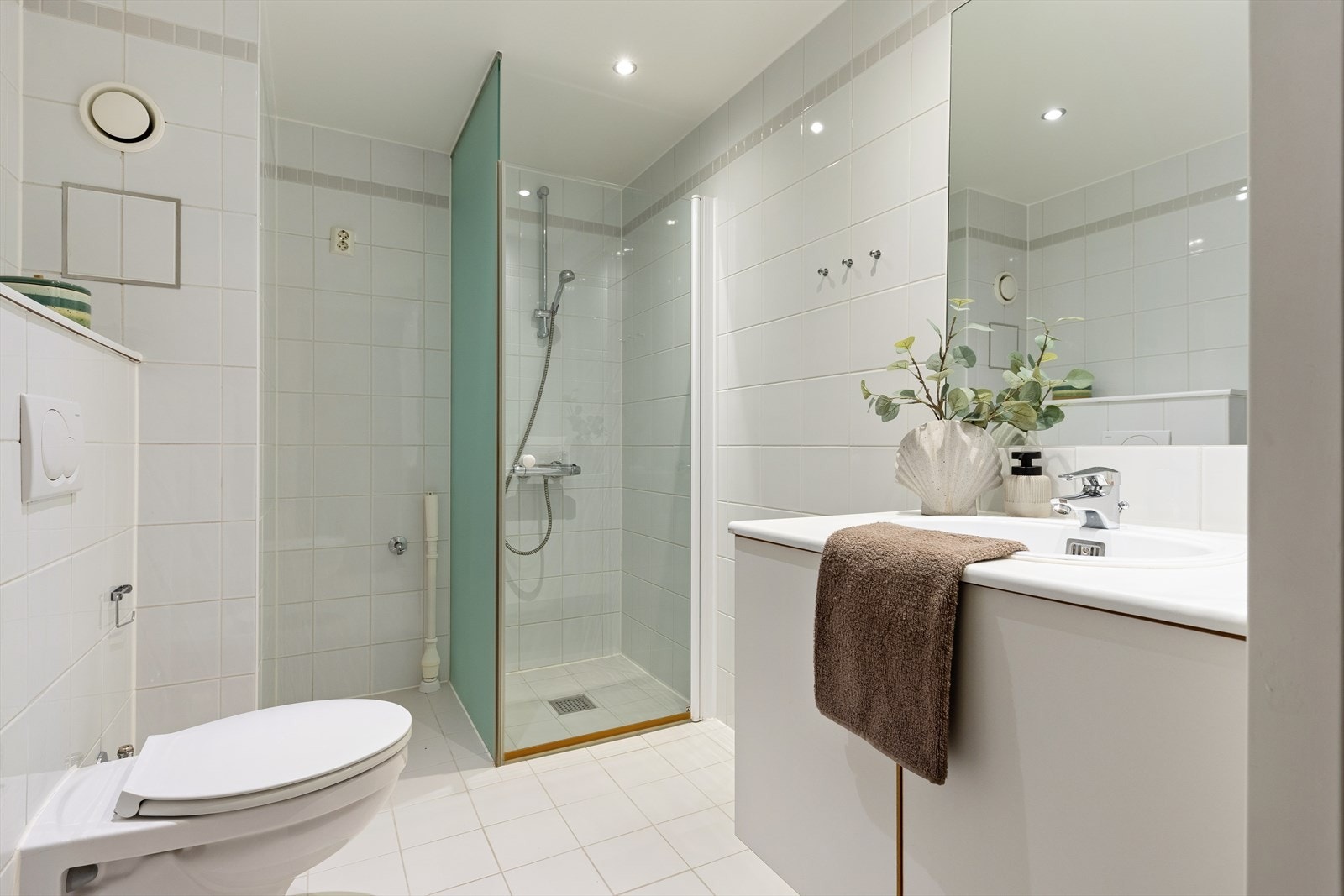 Helfliset baderom med vegghengt toalett, dusjhjørne, opplegg for vaskemaskin og tørketrommel Galleribilde