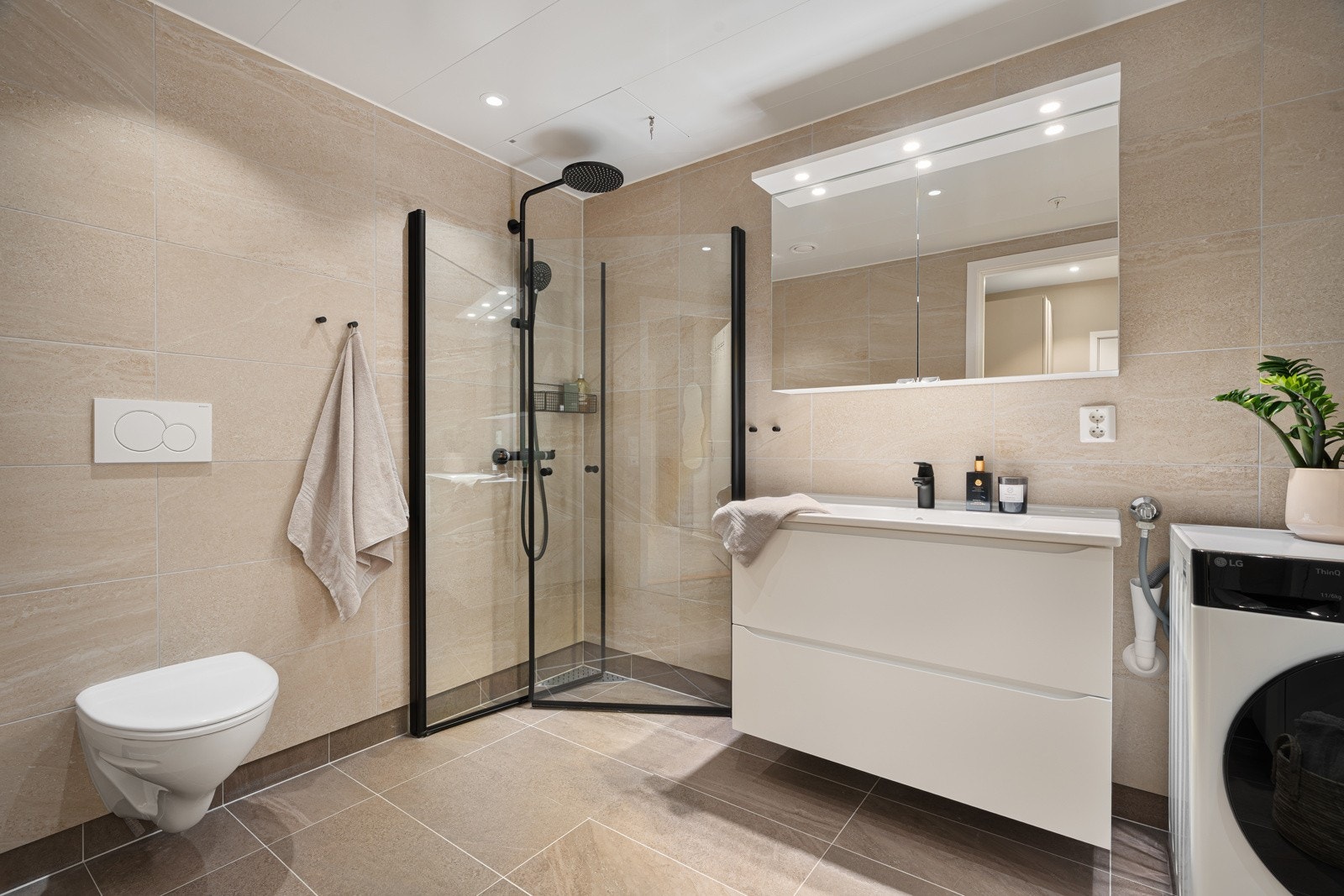 Lekkert, flislagt bad med stort dusjhjørne, vegghengt wc og opplegg for vaskemaskin. Galleribilde