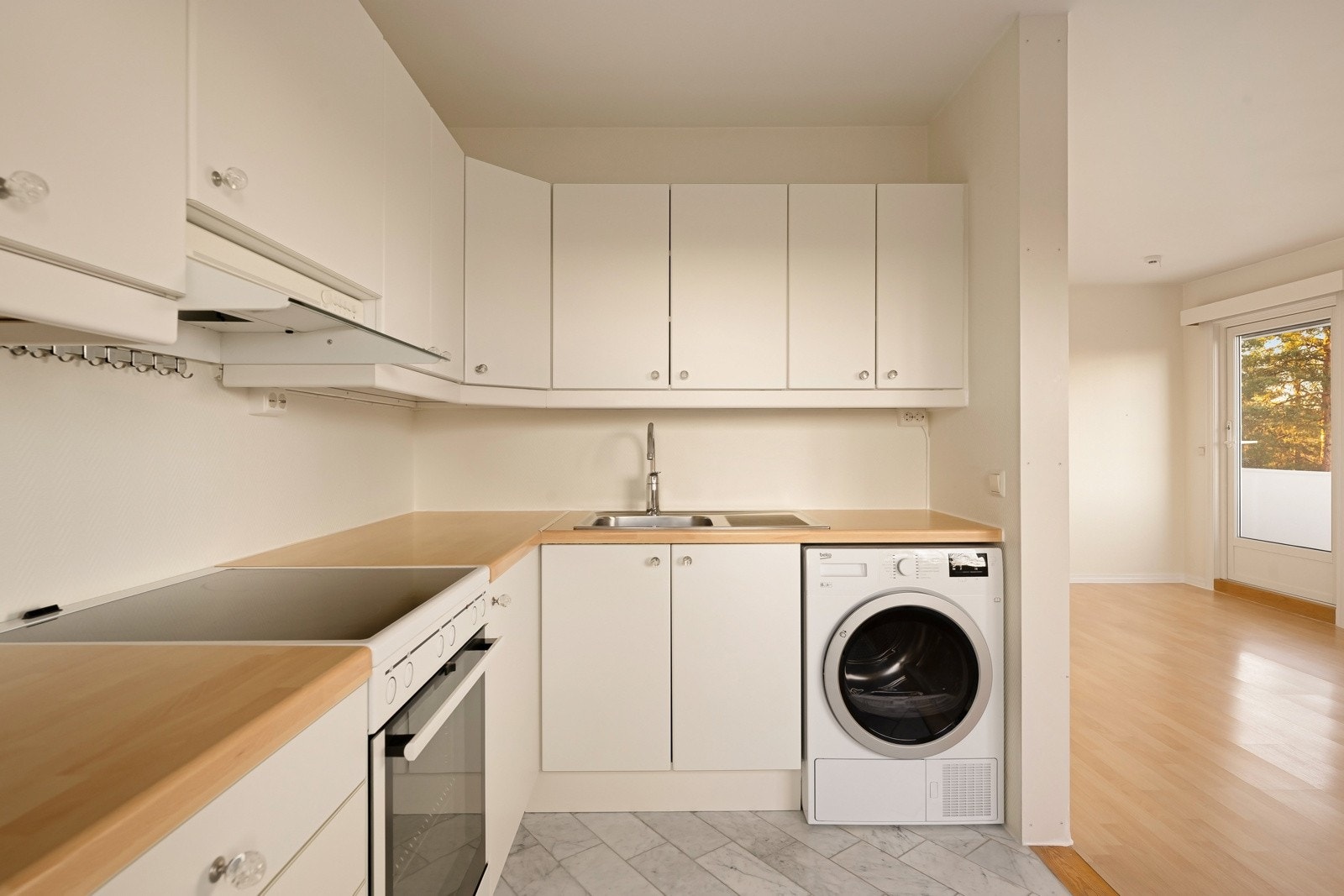 IKEA kjøkkeninnredning med glatte laminerte skapfronter, laminat benkeplate, enkel oppvaskkum med benkebeslag, ventilator og frittstående hvitevarer som komfyr, kjøl/- fryseskap. Galleribilde