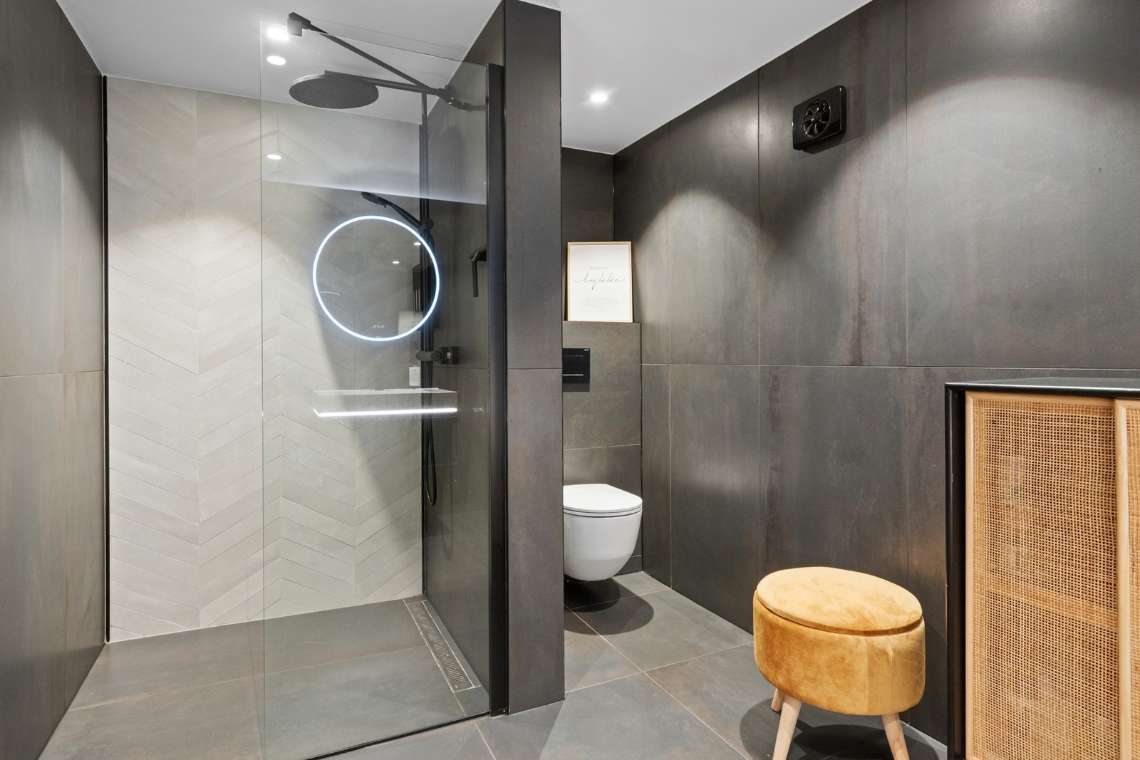 Badet ble pusset opp i 2020, og har store, mørkegrå vegg- og gulvfliser med et industrielt særpreg Galleribilde