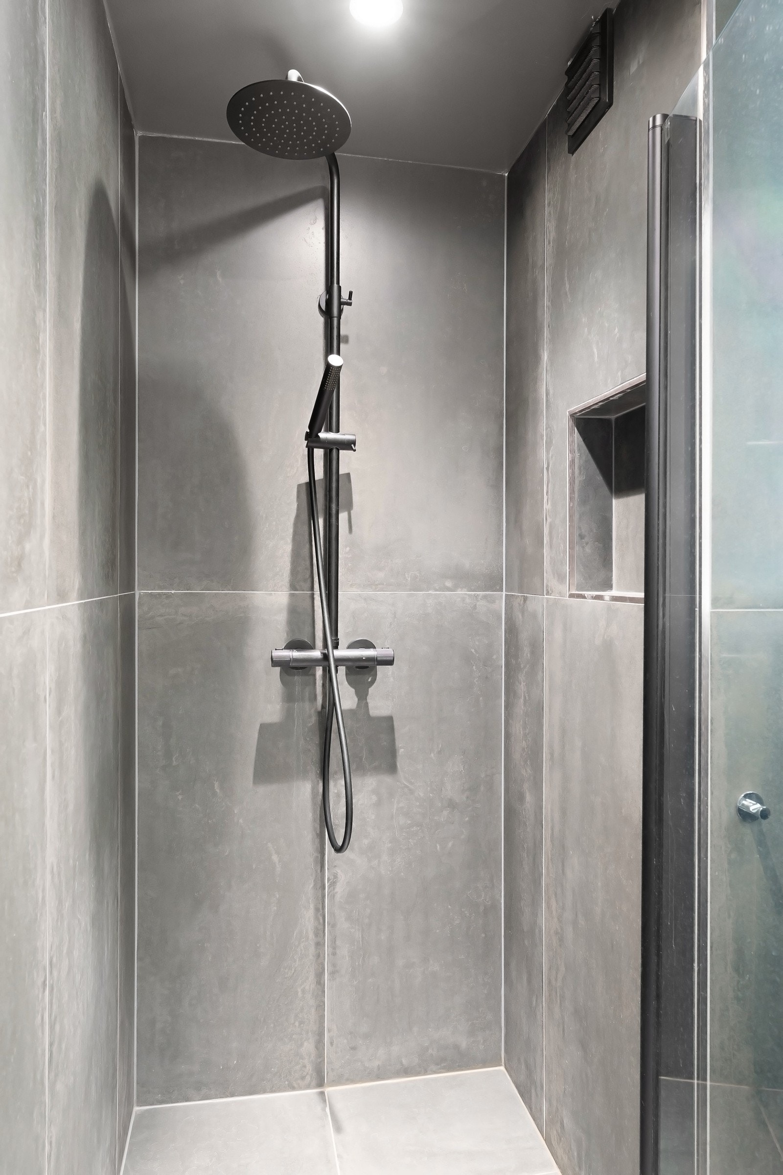 Dusjnisje med regnfallsdusj bak dusjdør i glass. Galleribilde