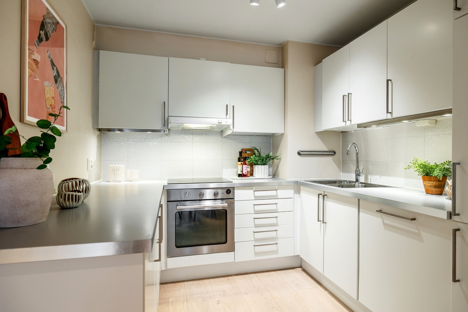 Kjøkkenet har glatte, hvite fronter fra IKEA og en laminert benkeplate med aluminiumskant. Innredningen er både stilren og praktisk, med god skap- og benkeplass. Galleribilde