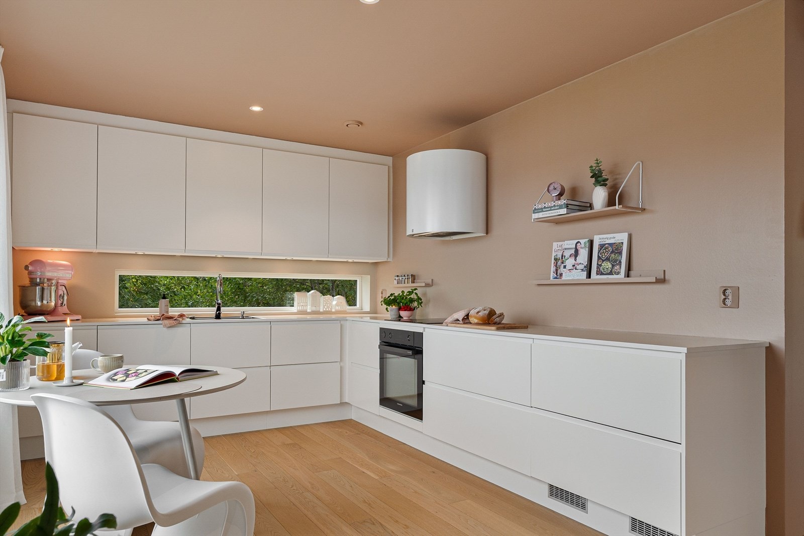 De åpne løsningene gir god plass til både matlaging og samvær, og de store vindusflatene slipper inn dagslys som fremhever de lyse tonene og den rolige atmosfæren. Galleribilde