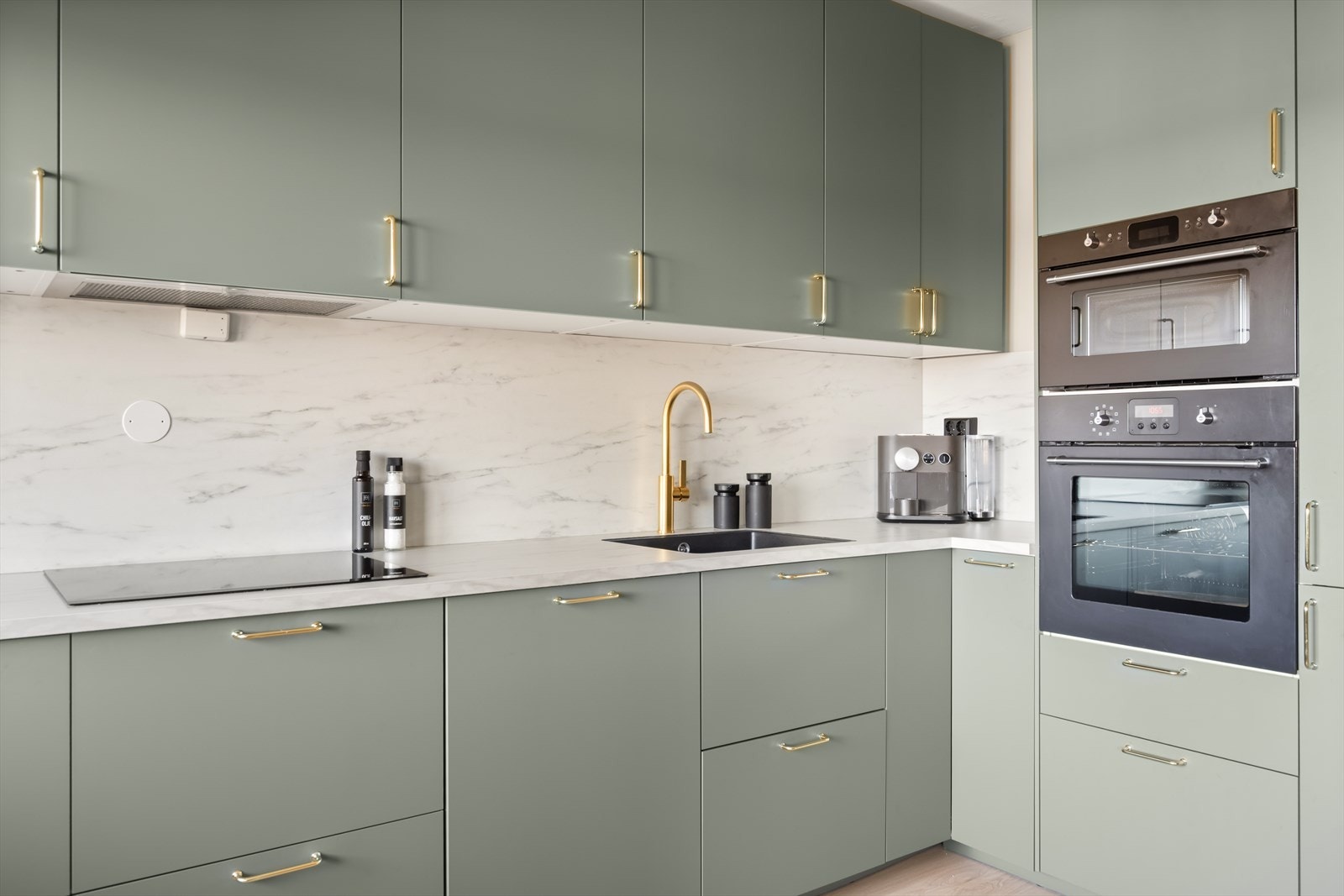 Stilig innredning med grønne fronter, laminatplate på vegg og benkeplate i laminat. Galleribilde