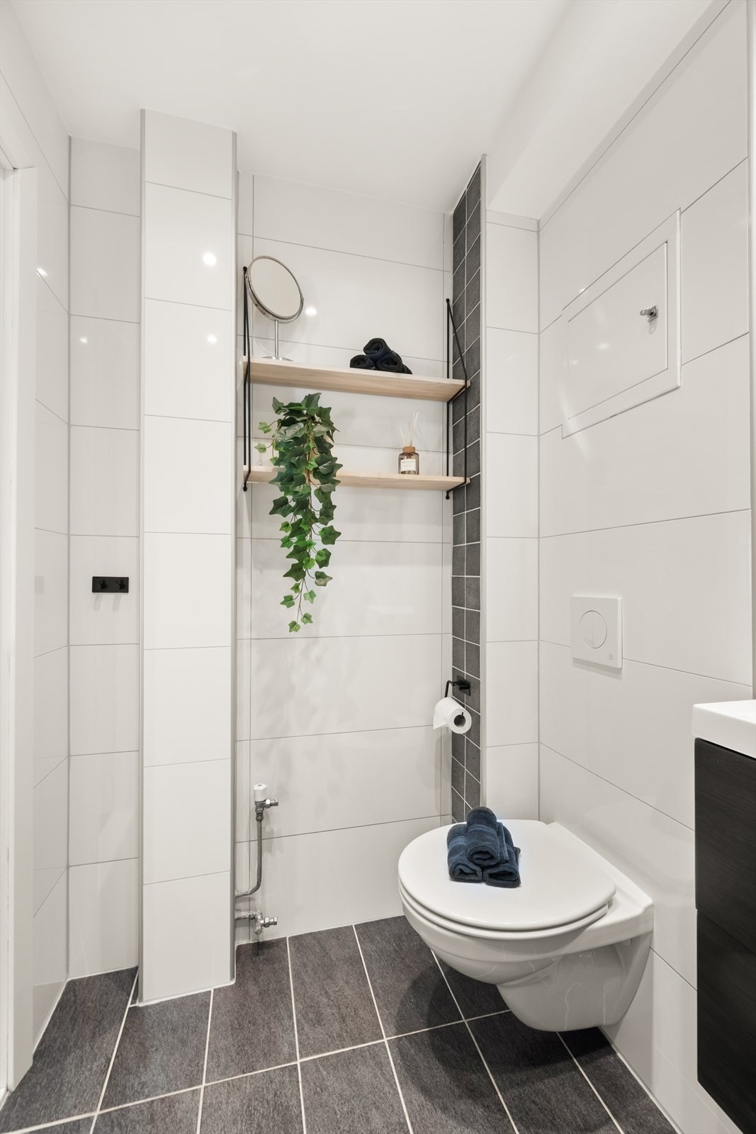 Rommet er innredet med vegghengt toalett, dusjhjørne med svingbare glassdører og baderomsinnredning med skuffer, servant nedfelt i innredningen og ettgrepsblandebatteri. Galleribilde