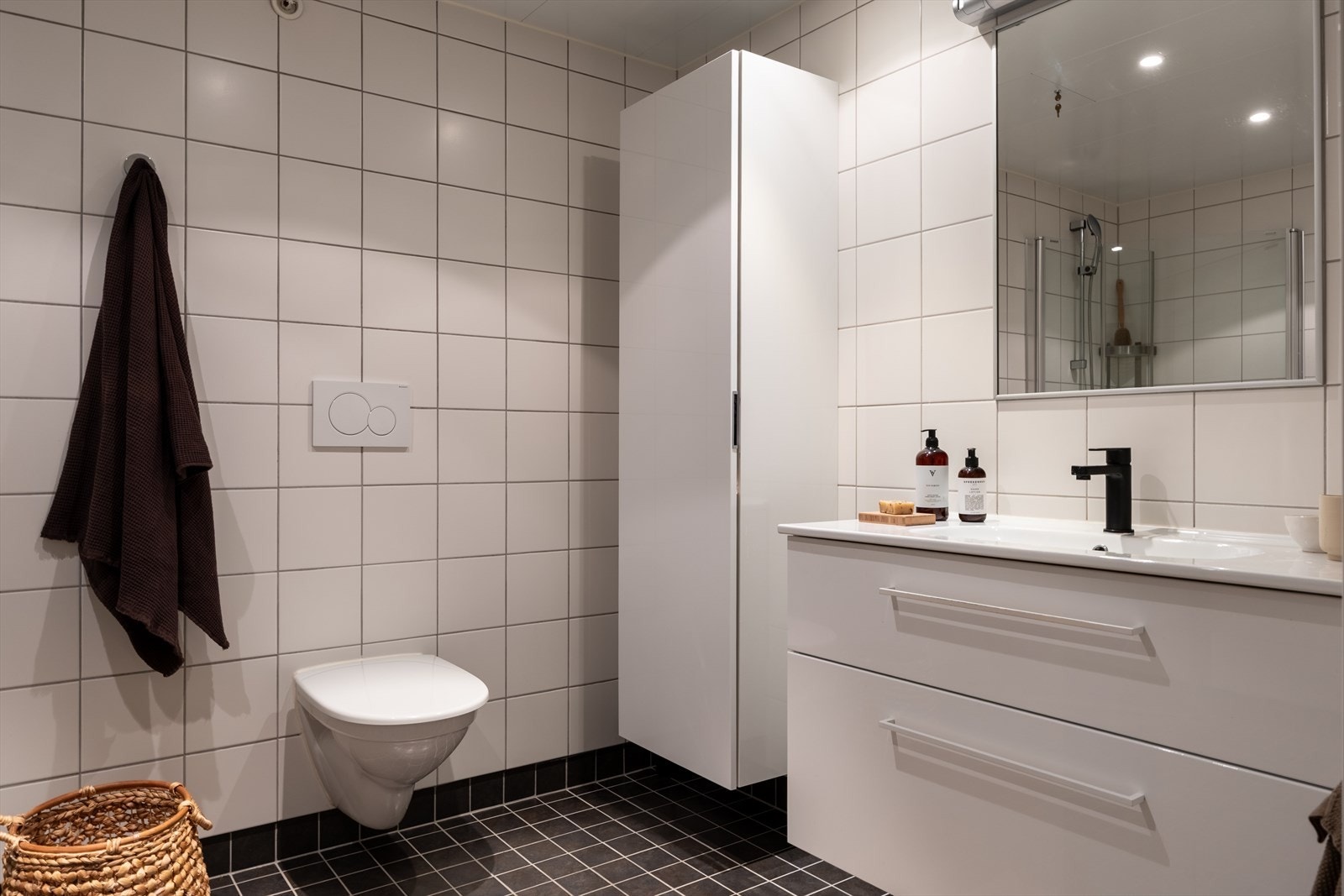 Vegghengt toalett og dusjhjørne med glassvegger gir effektiv utnyttelse av rommet. God skapplass med høyskap i tillegg til skuffer under servanten. Galleribilde