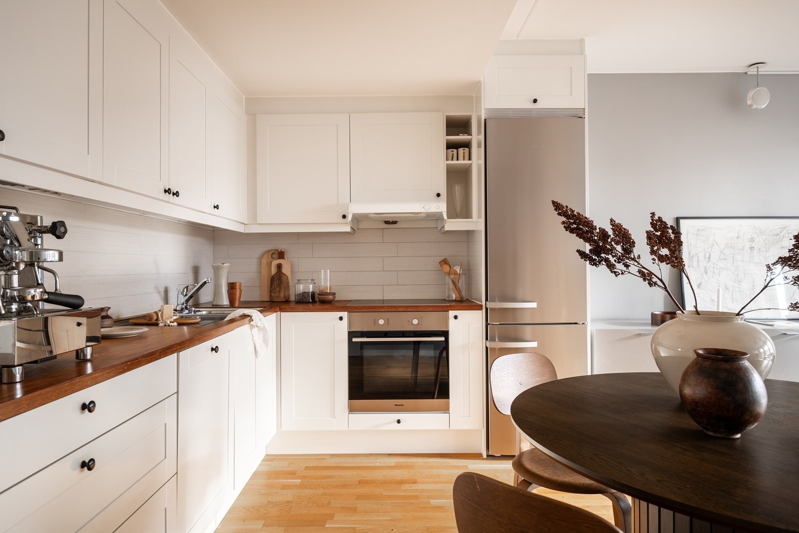 Kjøkkenet har stilren og klassisk innredning med profilerte hvite fronter og heltre benkeplate. Galleribilde