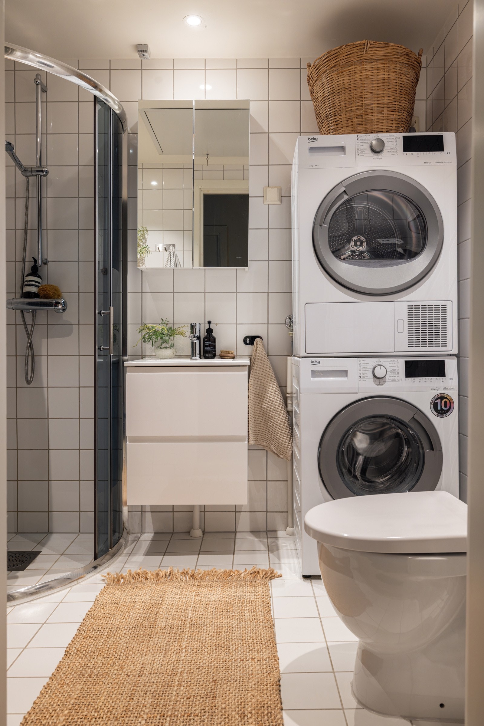 Moderne baderomsinnredning fra 2022 med skuffer og heldekkende servant, samt speilskap fra 2022 over. Baderommet er også utstyrt med dusjhjørne med skyvedører av glass og gulvstående toalett. Galleribilde