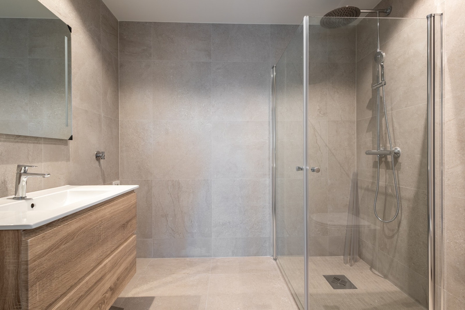 Lekkert bad med smakfulle materialer og moderne funksjonalitet. Badet er innredet med servantinnredning, speil, opplegg til vaskemaskin og dusjhjørne. Galleribilde