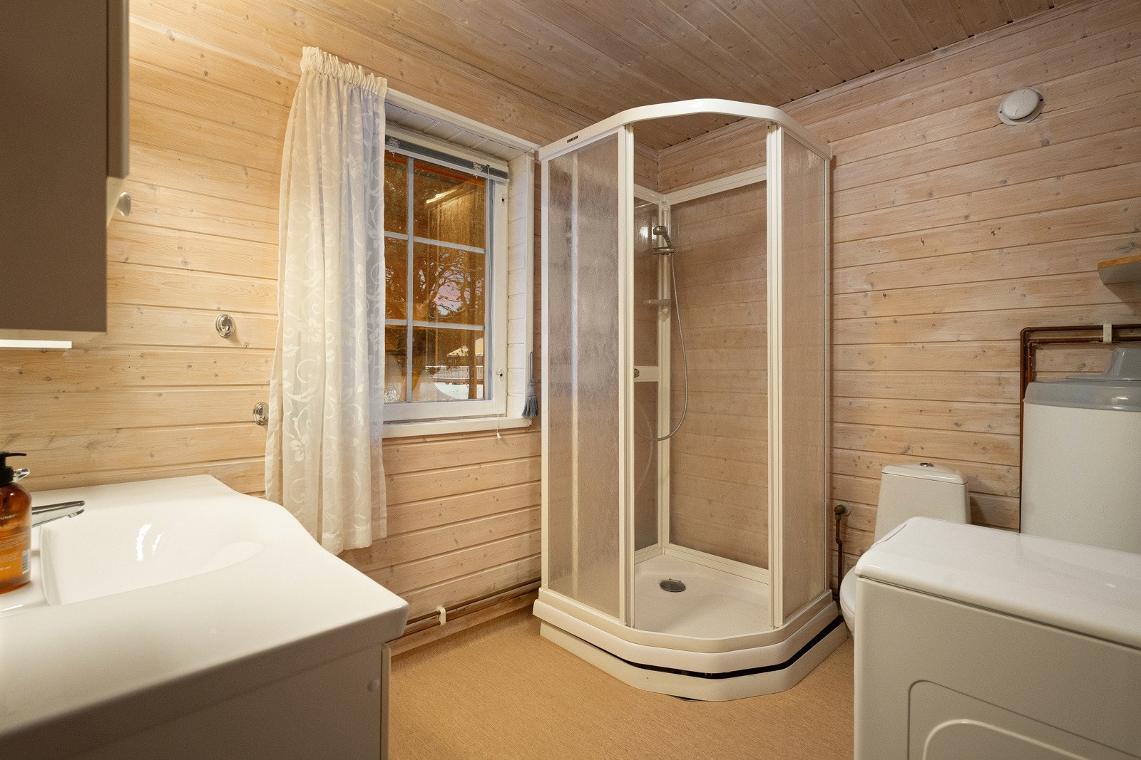 Badet er praktisk utformet med plass til alle dagligdagse gjøremål og er innredet med dusjkabinett, vegghengt servant og opplegg til vaskemaskin. Galleribilde