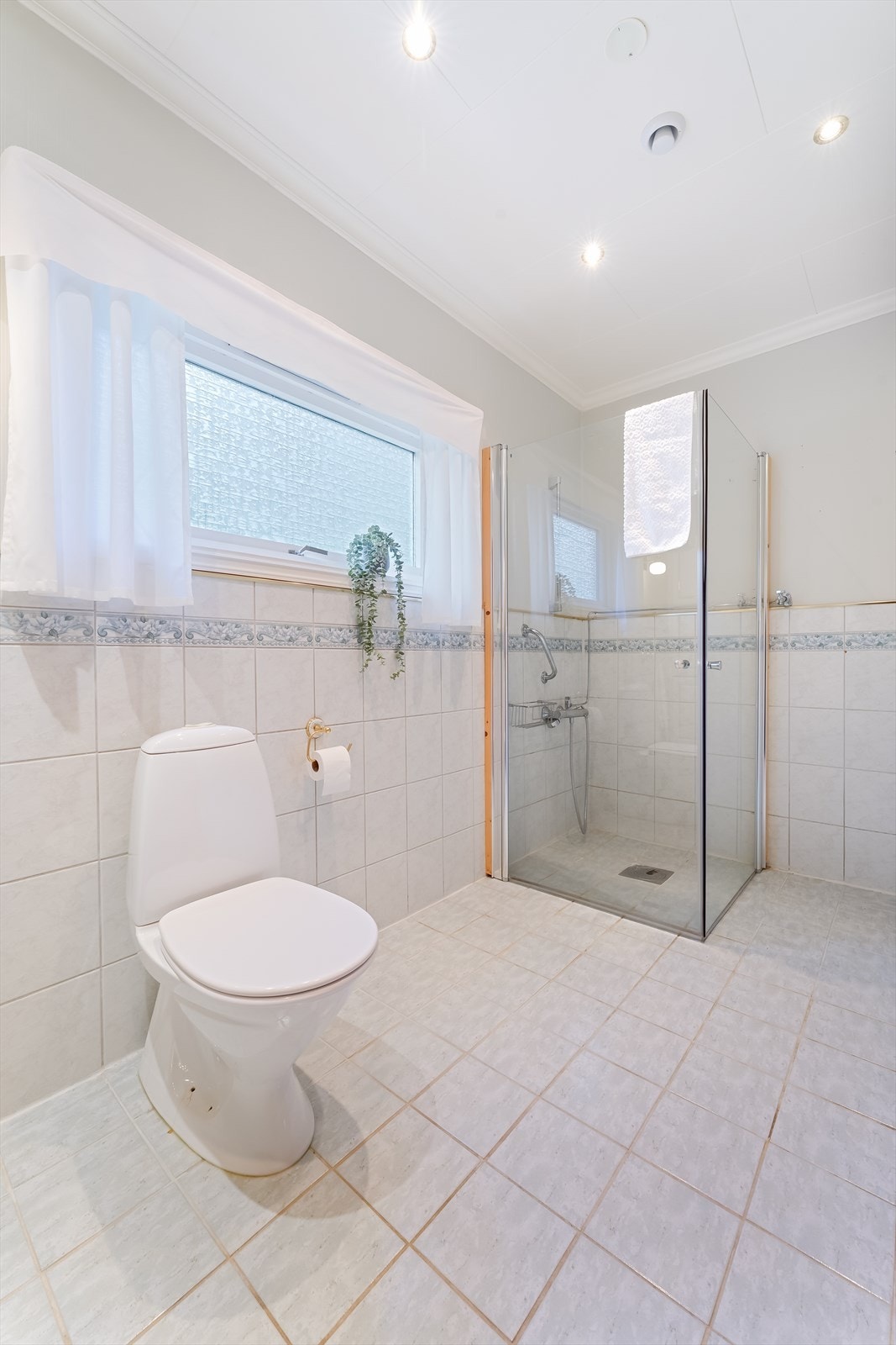 Badet er innredet med gulvmontert toalett, dusjhjørne og baderomsinnredning Galleribilde