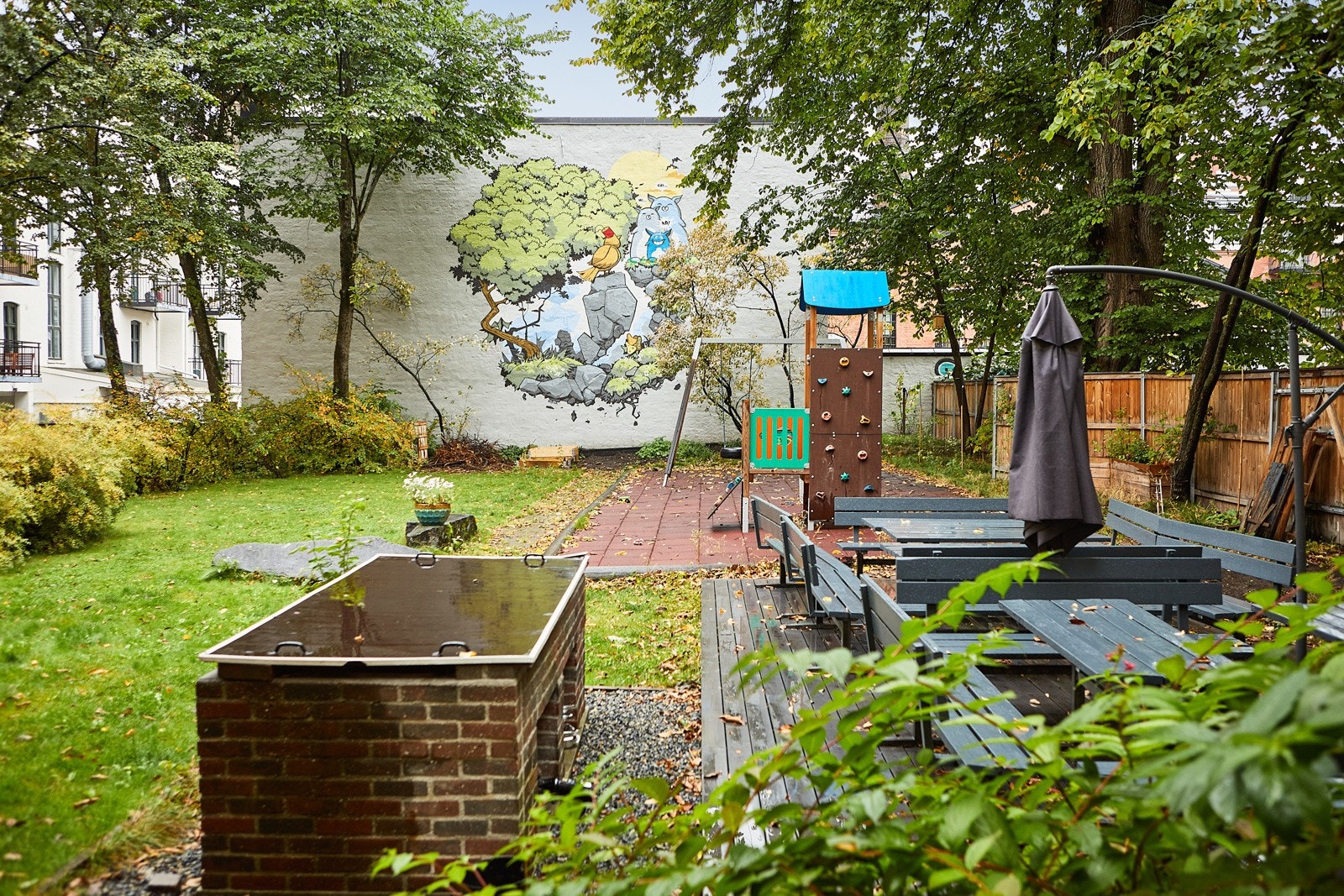 Felles tomt for borettslaget i bakgård bestående av trær, busker, diverse beplantning, plenområder, sittegrupper, sykkelparkering, lekeapparater, grillplass og asfalterte internveier. Galleribilde