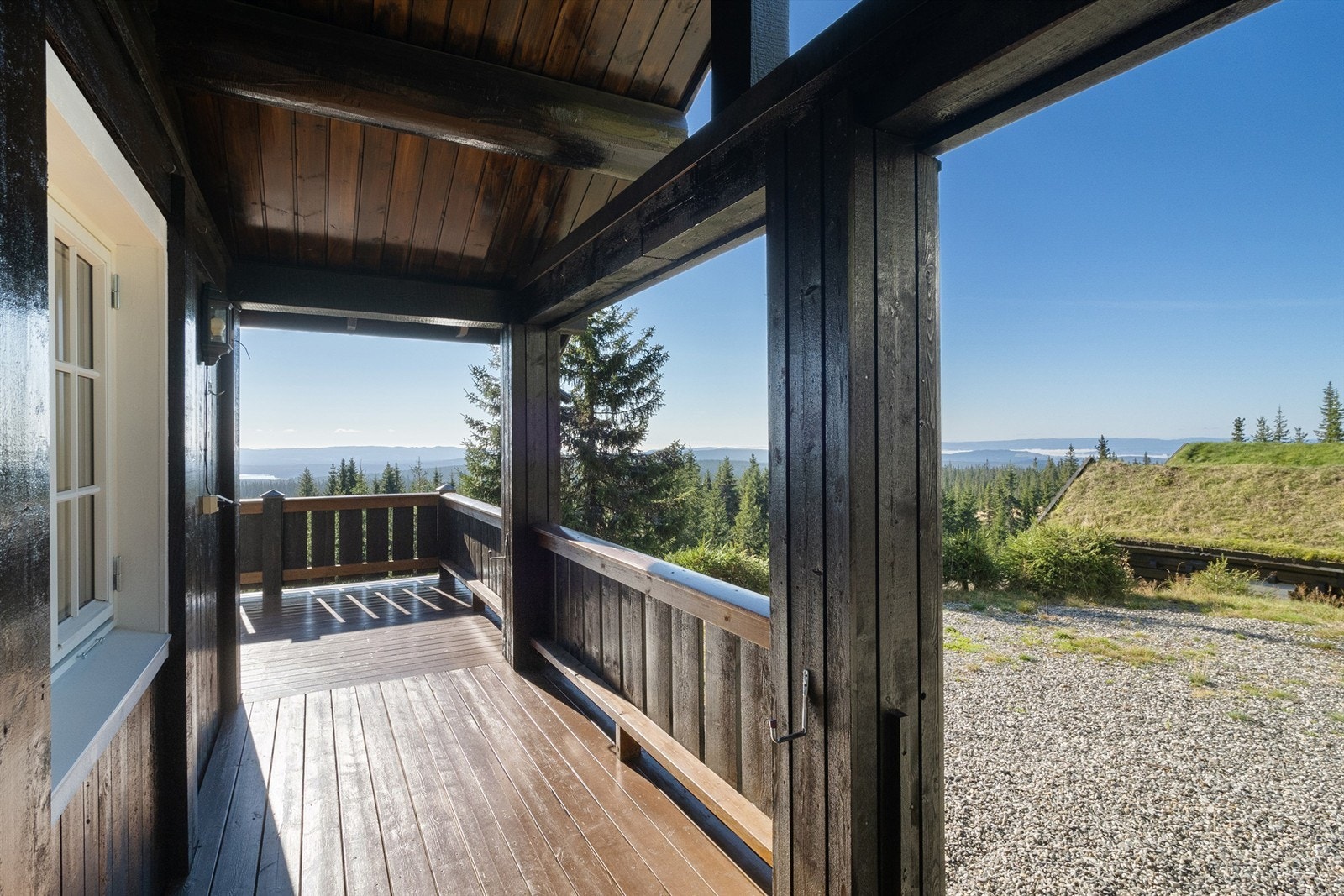 Terrassen strekker seg rundt sør og vestside av hytta og den delen mot vest er overbygget med tak. Det er etablert en praktisk krok for vedoppbevaring under taket. Galleribilde