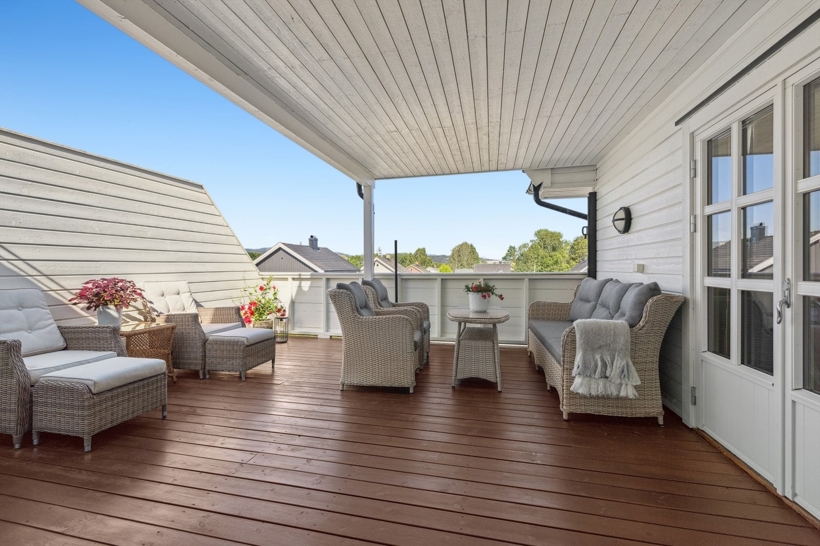 Terrassen er delvis overbygget og utformet med levegger og lukket rekkverk, noe som gir en lun og skjermet atmosfære. Galleribilde