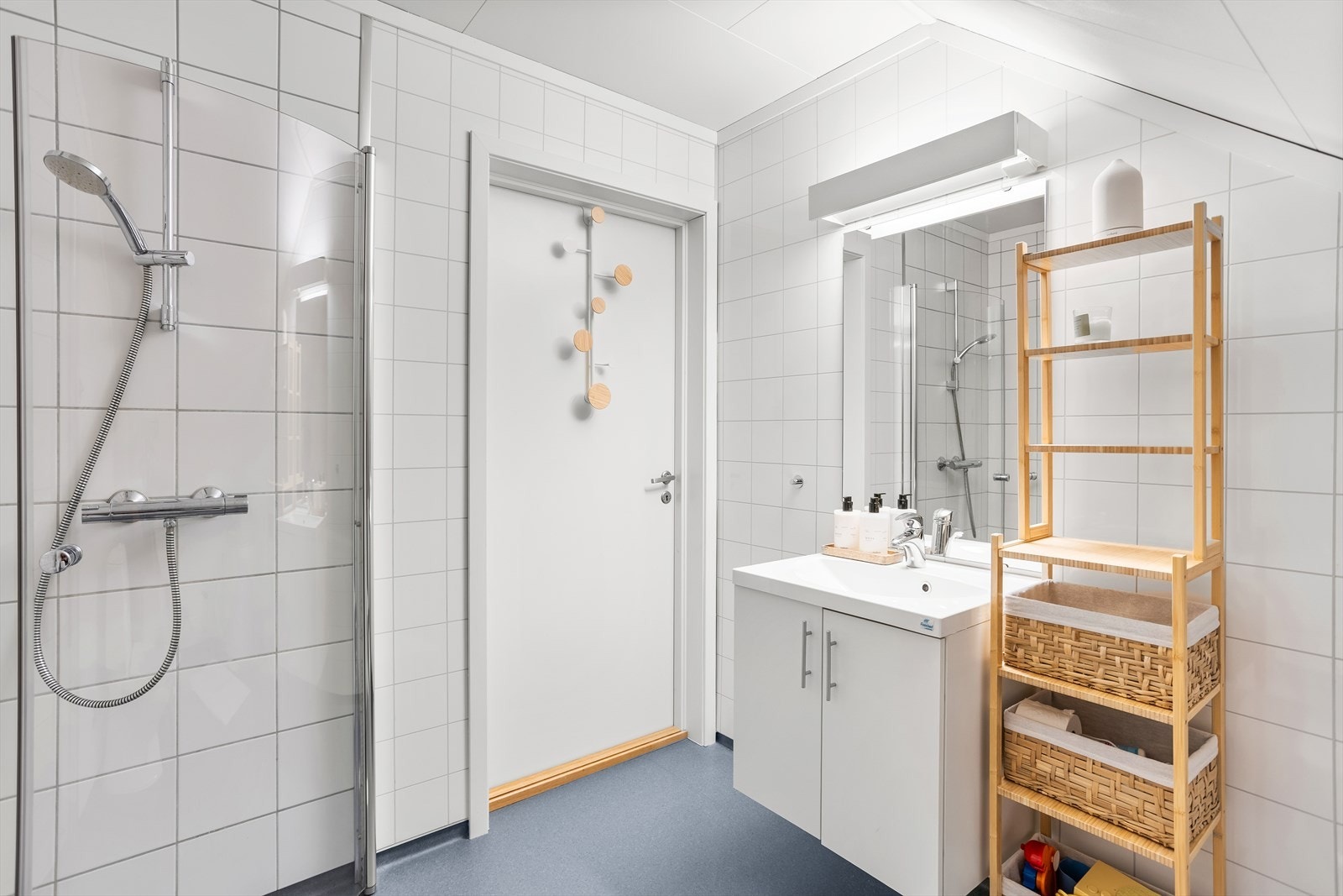 Badet er innredet med hvit servantinnredning med skapseksjon, speil, gulvstående toalett og dusjhjørne med glassdører. Galleribilde