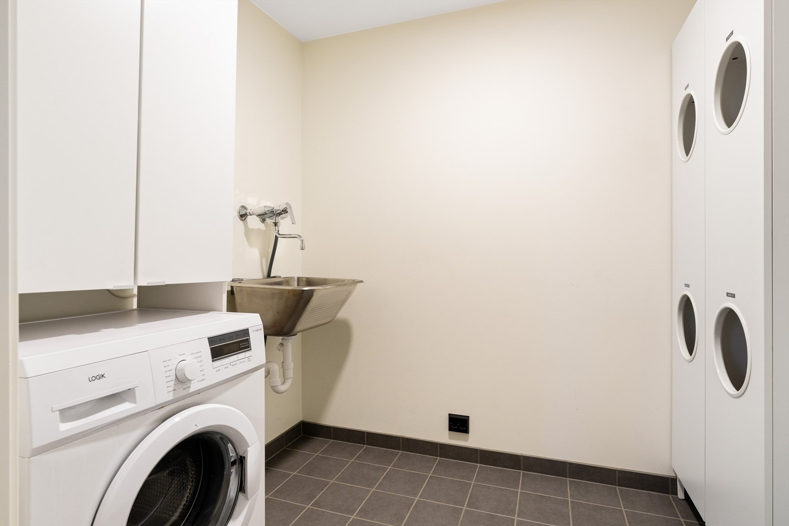 Et praktisk separat vaskerom som bidrar til en ryddig og funksjonell hverdag. Flislagt gulv med sluk, opplegg for vaskemaskin/tørketrommel og utslagsvask. Dobbeltstikk klart dersom man ønsker å ha tørketrommel over eller vedsiden av vaskemaskinen. Galleribilde