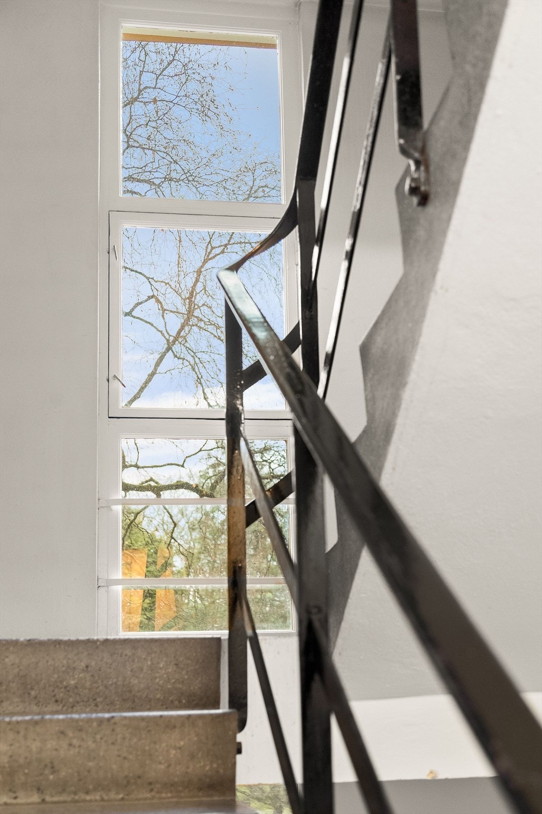 Funkisdetaljer fra avsatsen utenfor leiligheten med store vinduer og utsikt til trær og grønt. Galleribilde