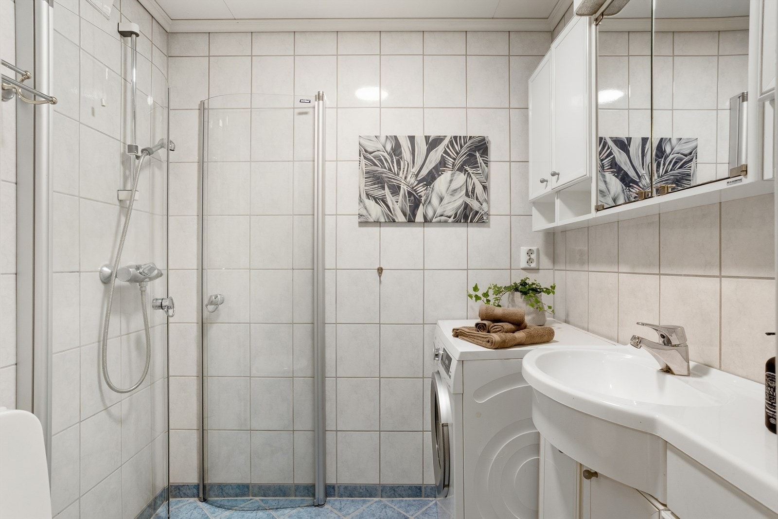 Baderomsinnredningen består av dusjhjørne med glassdører som slår innover når dusjen ikke er i bruk. Galleribilde