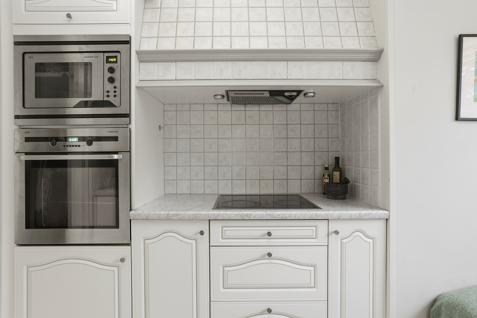 Det er flislagt mellom under- og overskap, samt utenpå ventilatoren. Galleribilde