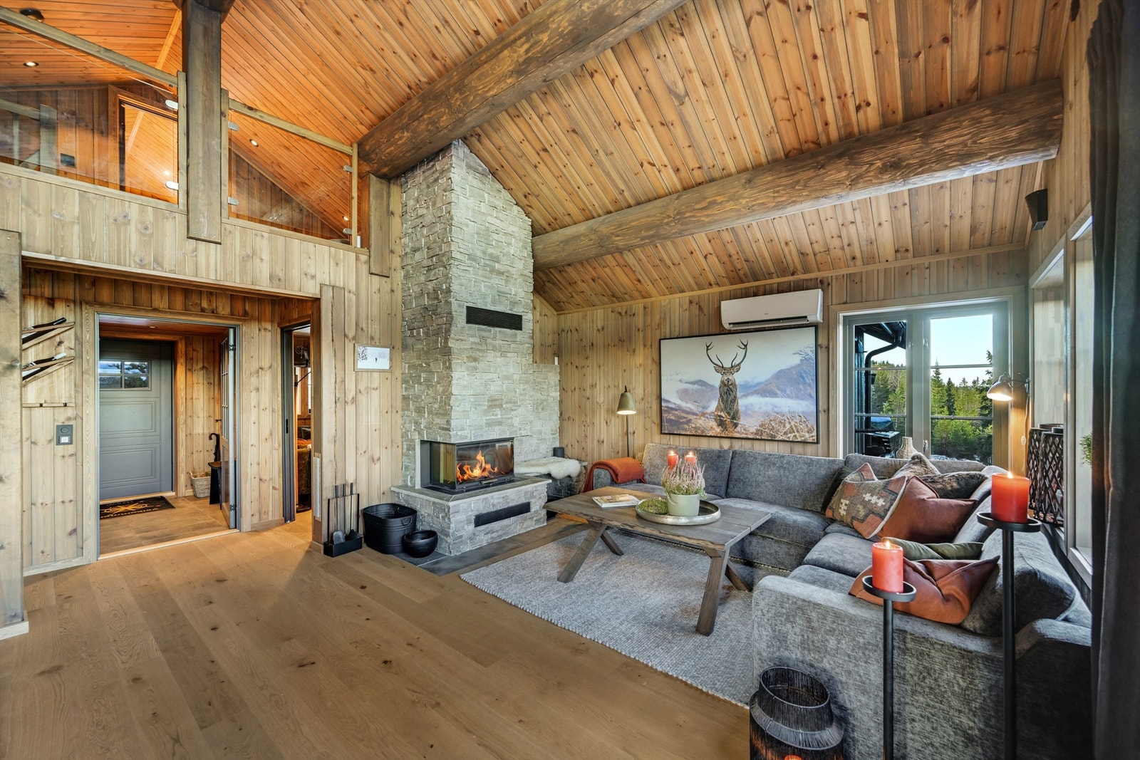 Innbydende og moderne stue med svært god takhøyde og en fantastisk peis - plassert som hyttas midtpunkt. Galleribilde
