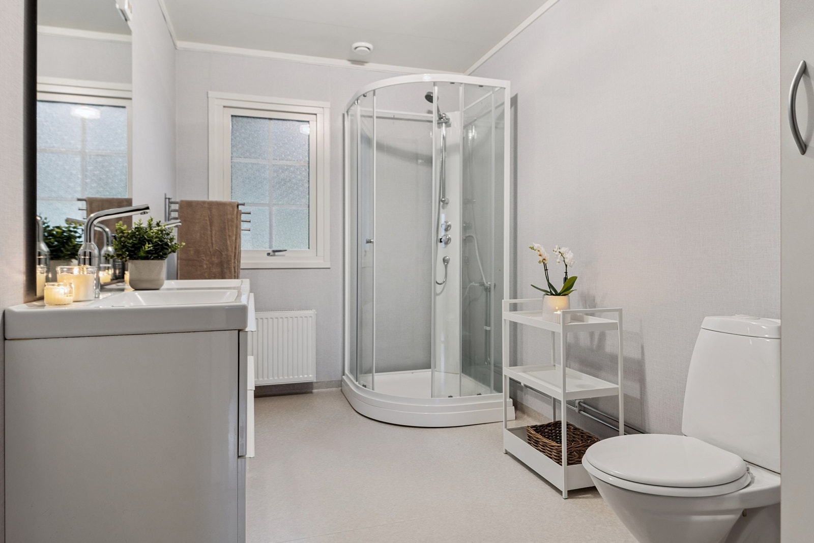 Badet er utstyrt med dusjkabinett, toalett og servant med dobbel kraner. Galleribilde