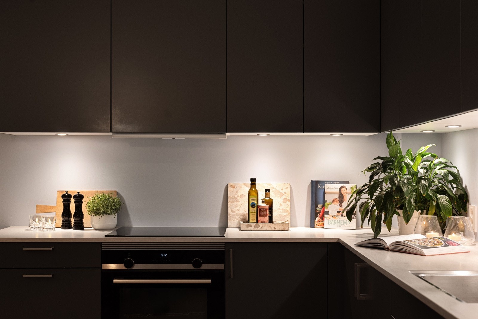 Den sorte innredningen har slette fronter, laminat benkeplate, ventilator og belysning under overskap. Galleribilde