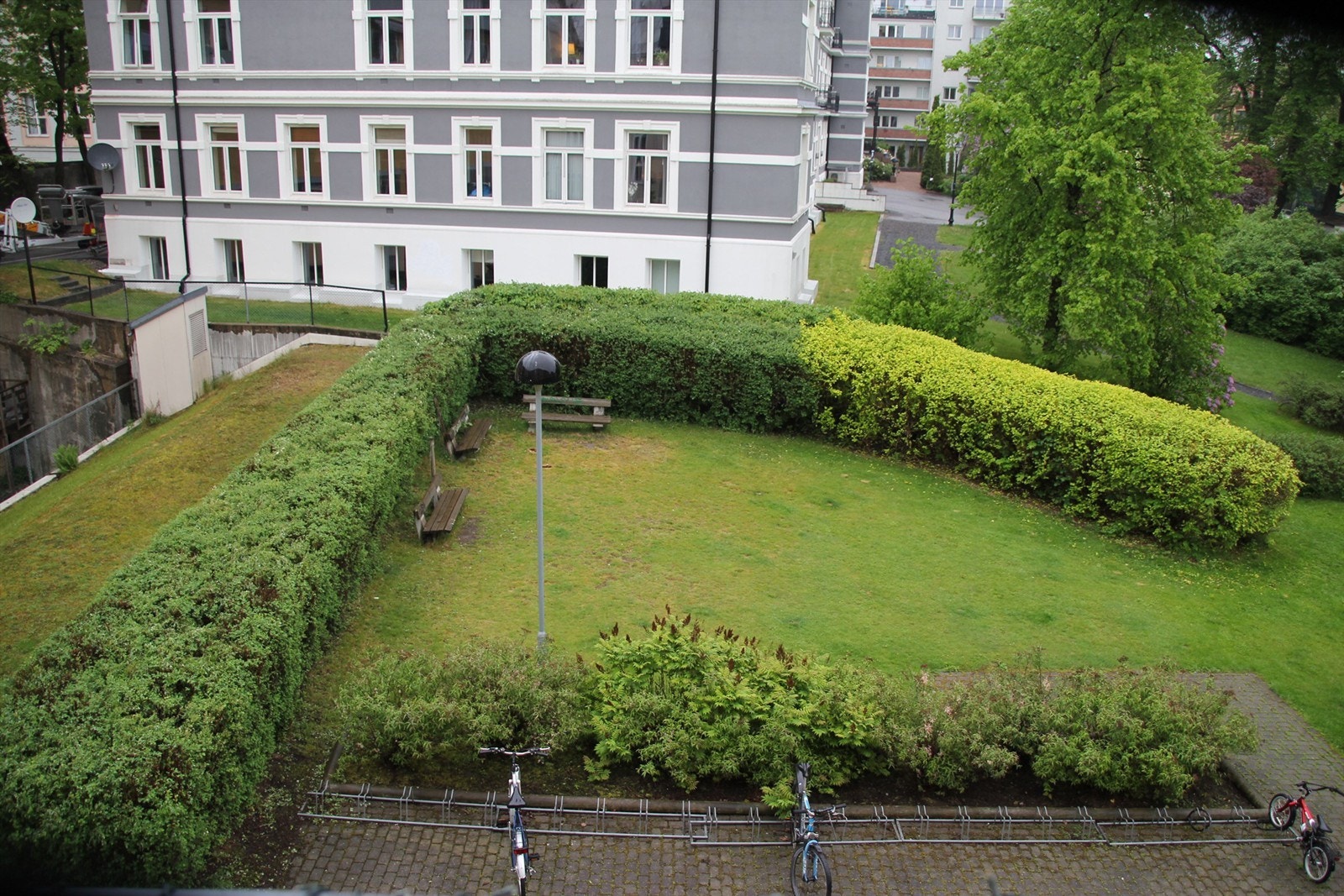 Frodig bakgård med sykkeloppstilling og beplanting. Galleribilde