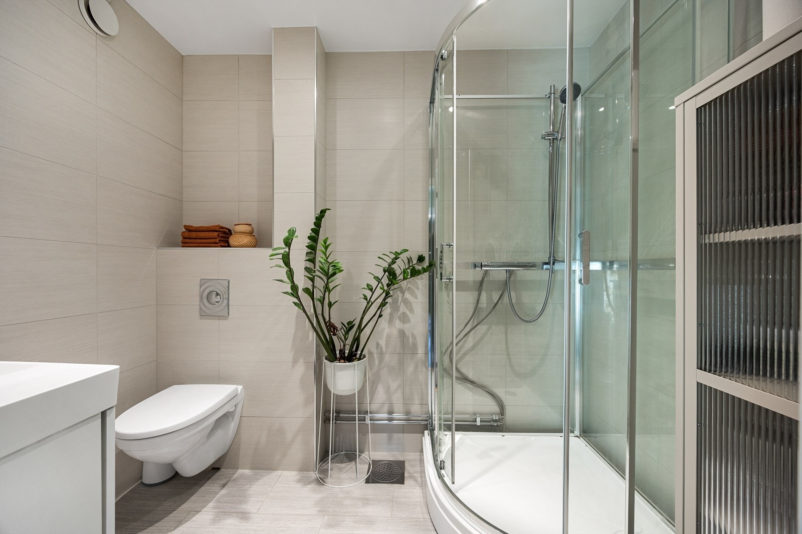 Badet er utstyrt med servantseksjon, vegghengt toalett og et praktisk dusjkabinett. Galleribilde