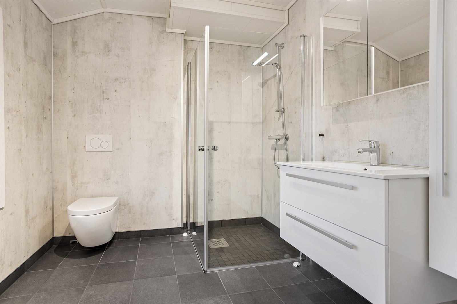 Lyst og moderne bad med stilrene overflater, vegghengt toalett, dusjkabinett, romslig servant og vegghengt skap. Perfekt for en funksjonell hverdag. Galleribilde