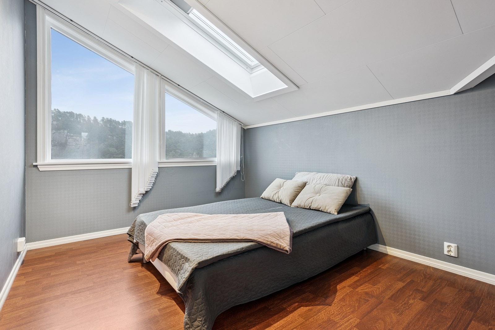 Lyst soverom med skråtak og store vinduer som slipper inn rikelig med naturlig lys, skaper en innbydende atmosfære. Galleribilde