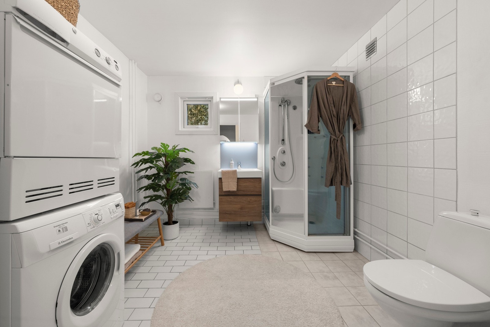 Bad med flislagte overflater og en praktisk innredning som gir et ryddig og funksjonelt uttrykk. Galleribilde