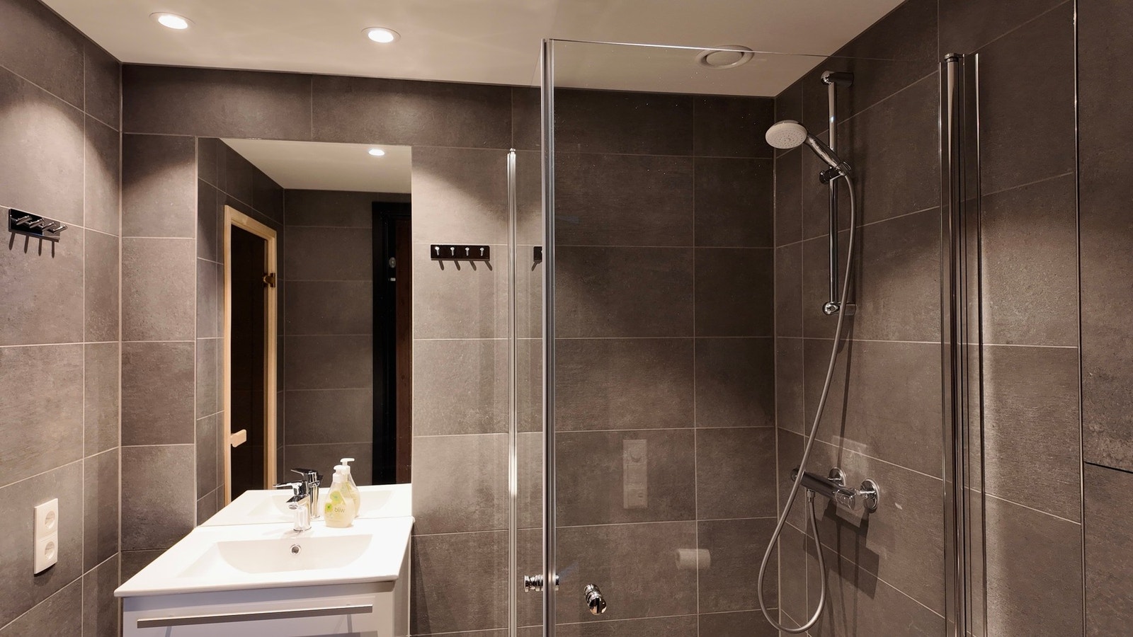 Leiligheten har to delikate flislagte bad med baderomsinnredning, speil, dusj med vegger i herdet glass, og vegghengt WC Galleribilde