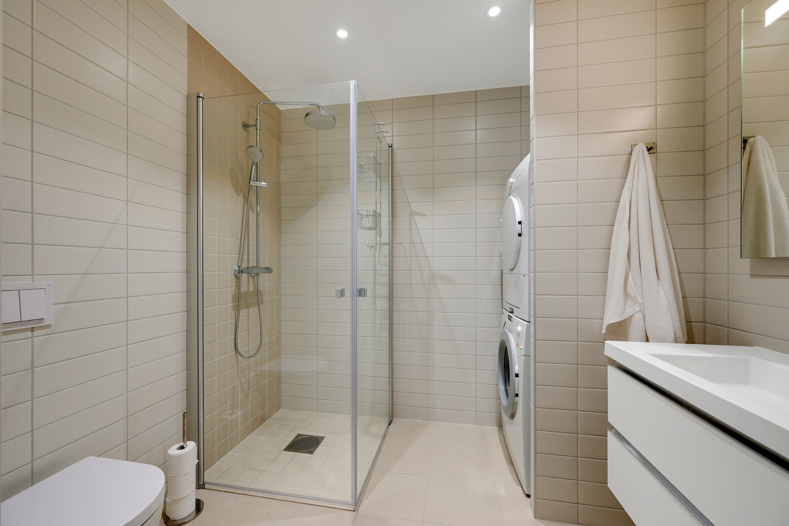 Bad 2 ligger med tilgang fra gangen. Her det toalett, dusjhjørne, vask i innredning, speil og opplegg for vaskemaskin med plass til tørketrommel Galleribilde