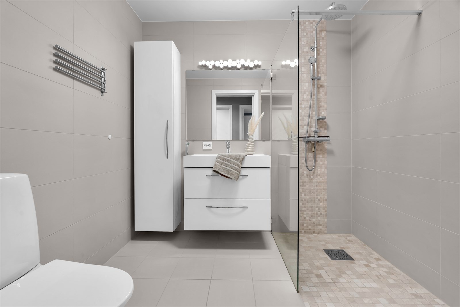 Bad 2 er romslig og flislagt med dusjhjørne med glassvegger, baderomsinnredning og toalett. Galleribilde