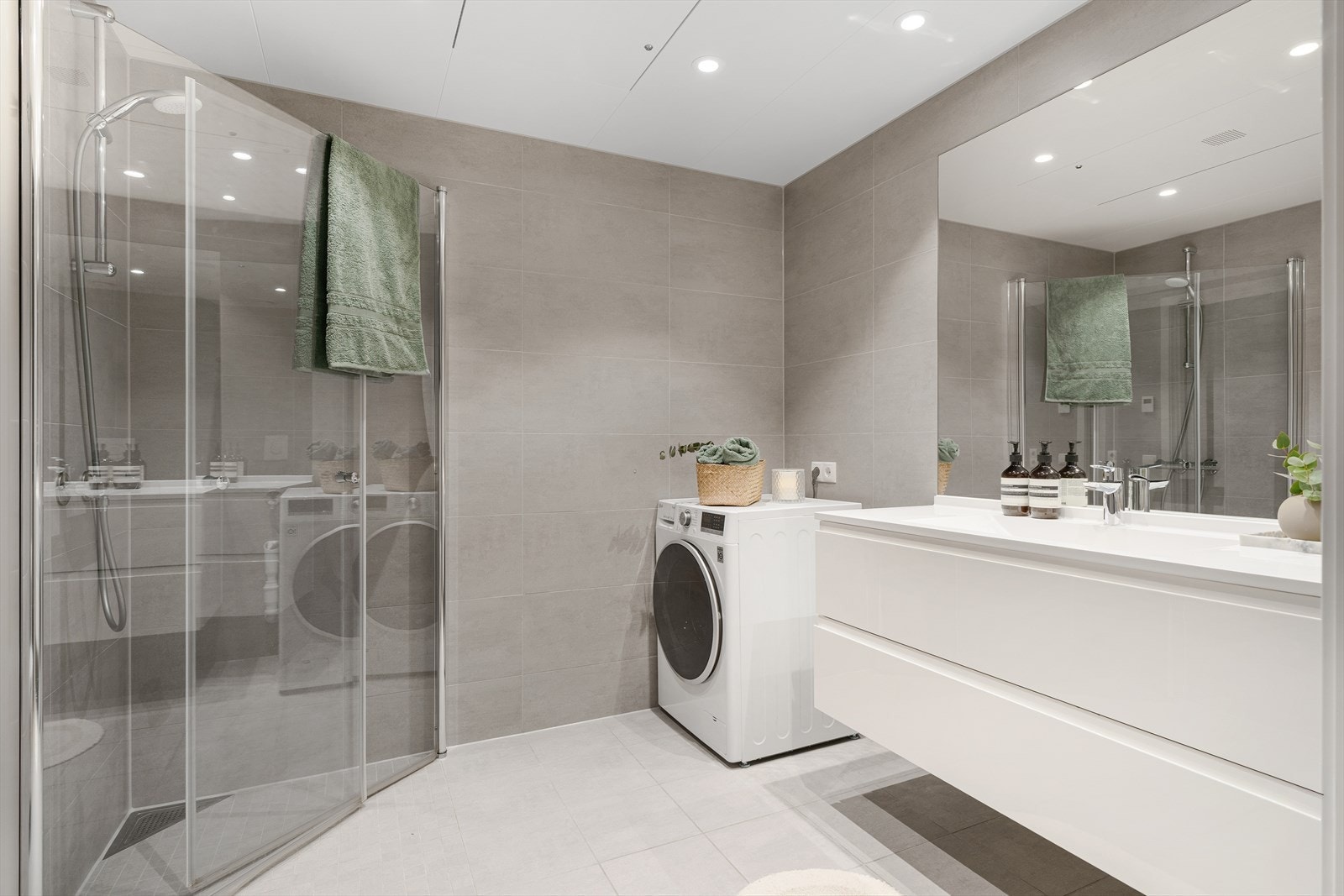 Utsøkt bad med betonggrå fliser, downlights i himling og vannbåren varme i gulv. Galleribilde