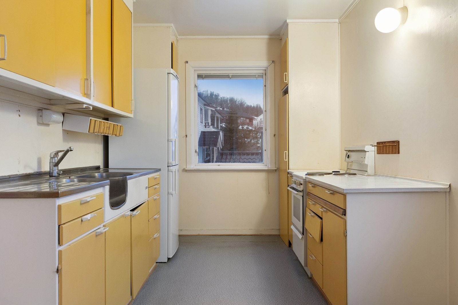 Kjøkkeninnredning med gule slette fronter, laminat benkeplate og benkebeslag i stål. Galleribilde