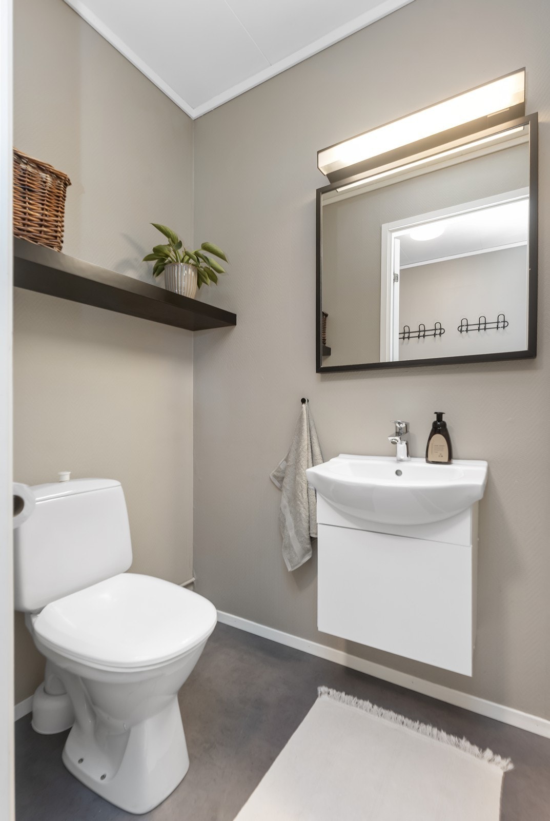 Toalettrom er tidløst og lekkert innredet med belegg på gulv, beige vegger og detaljer i både hvitt og sort. Galleribilde