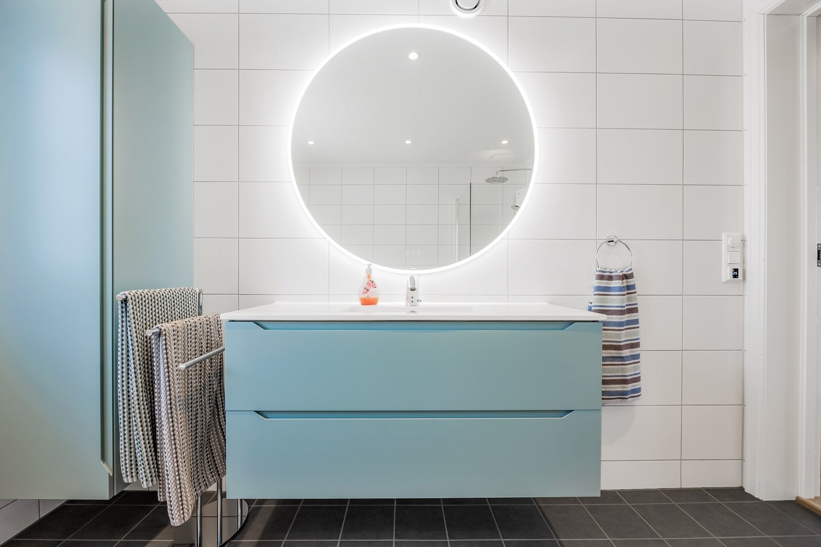 Servant i moderne baderomsinnredning med skuffer, og speil med integrert belysning. Galleribilde