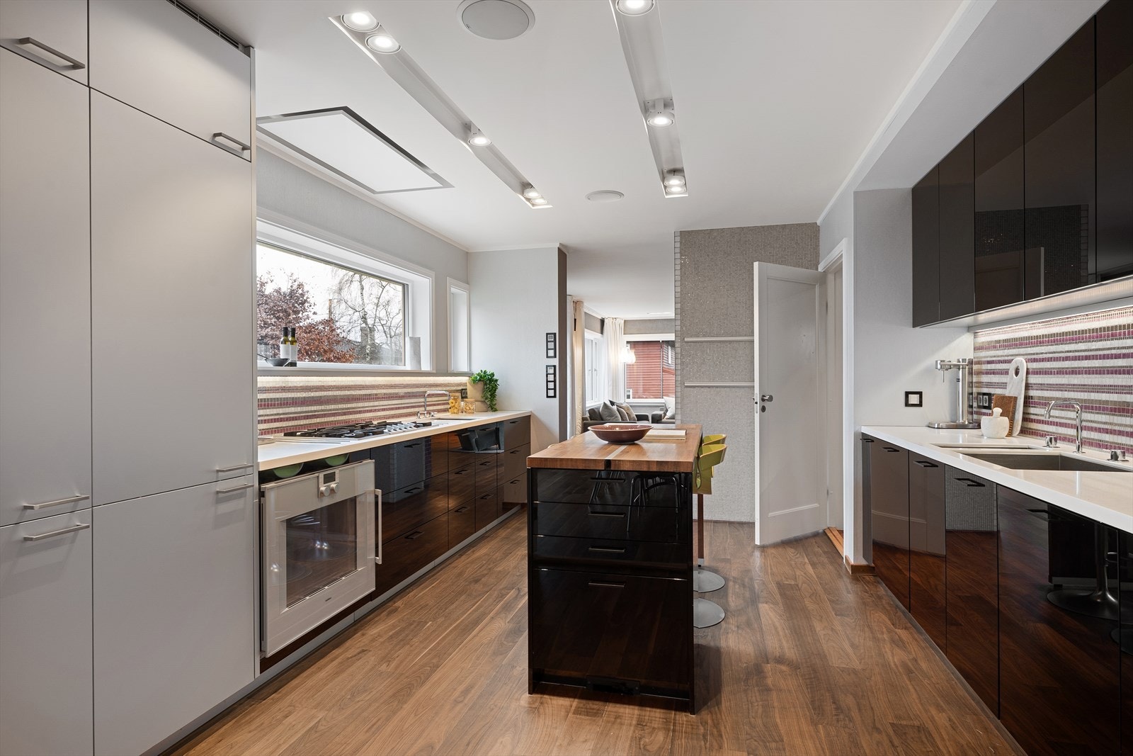 Poggenpohl kjøkkeninnredning med Corian benkeplate med underlimte kummer og mosaikkfliser over benk. Galleribilde