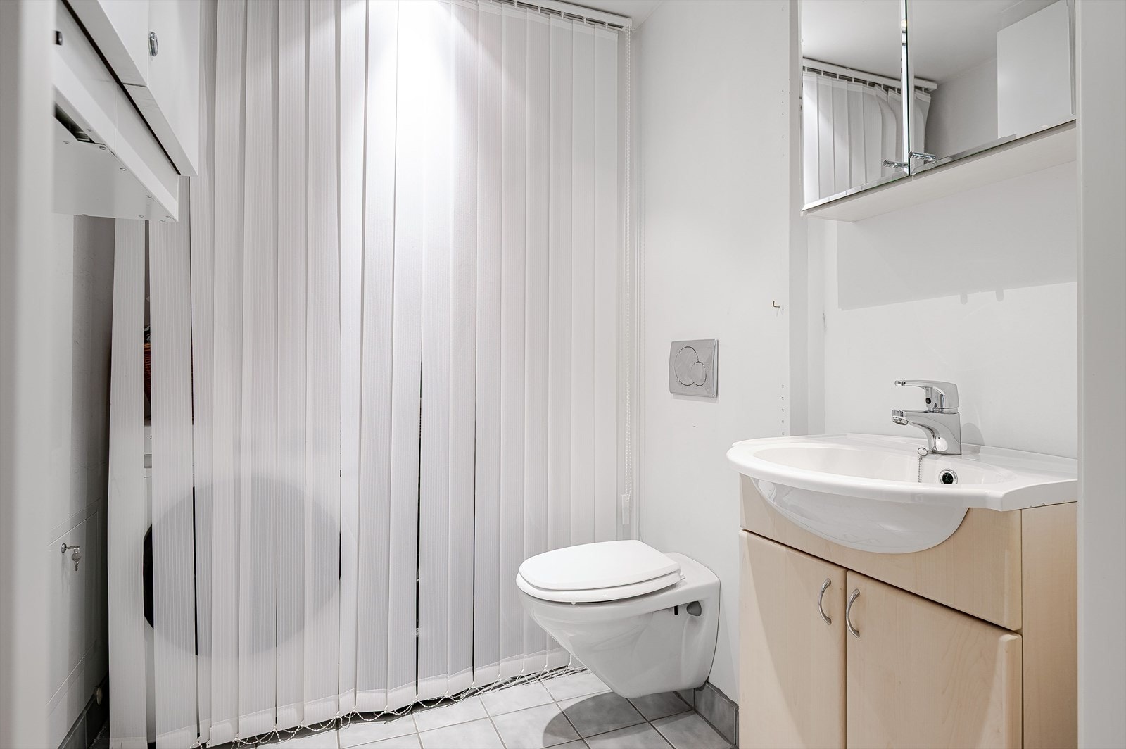 Leiligheten har også et praktisk toalettrom kombinert med vaskerom. Rommet har flislagt gulv med vannbåren gulvvarme, glatte lysmalte overflater, downlights i himlingen og avtrekk via balansert ventilasjon. Galleribilde