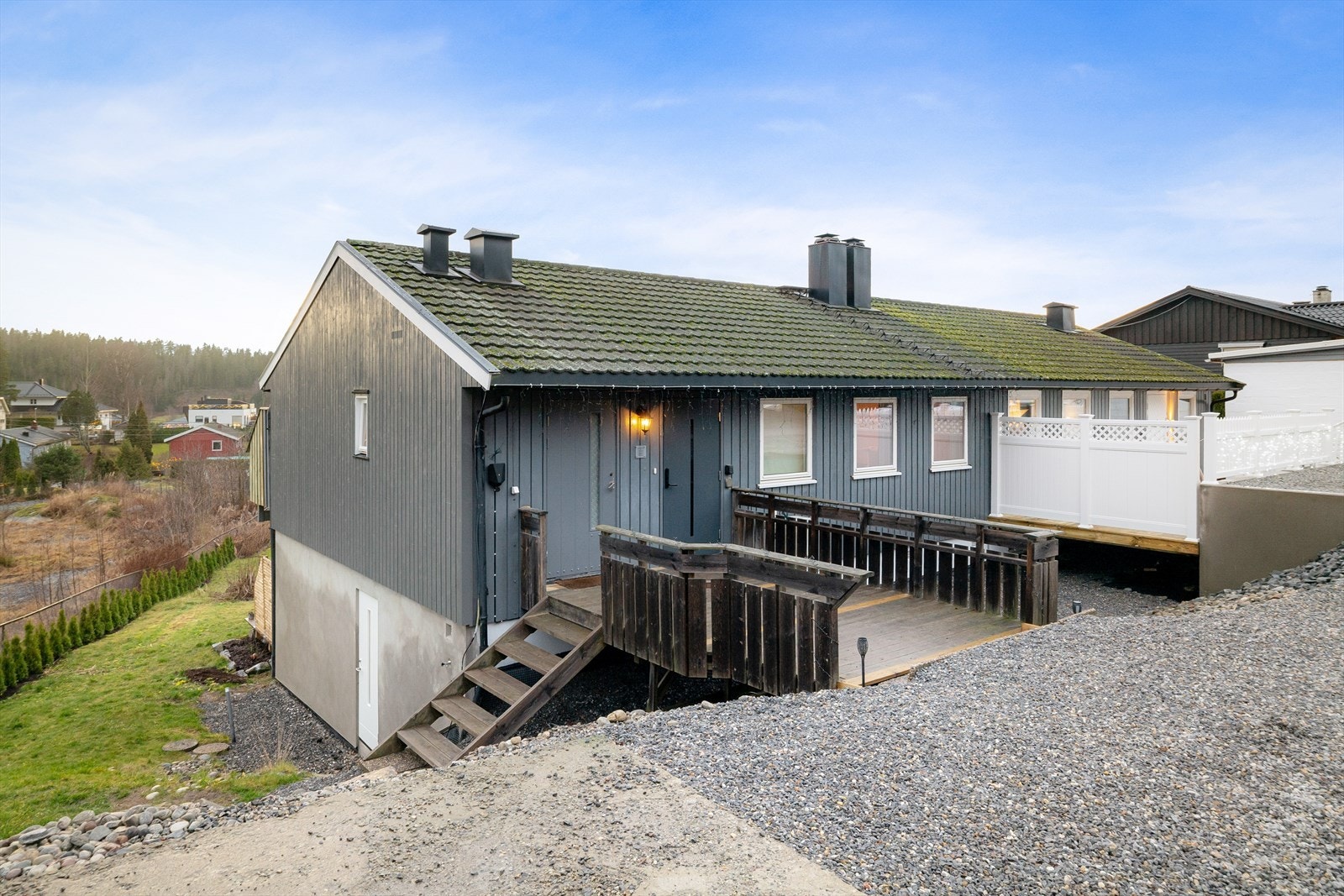 Inngangsparti med terrasse. Det er parkering for flere biler og ladeboks for elbil montert. Galleribilde